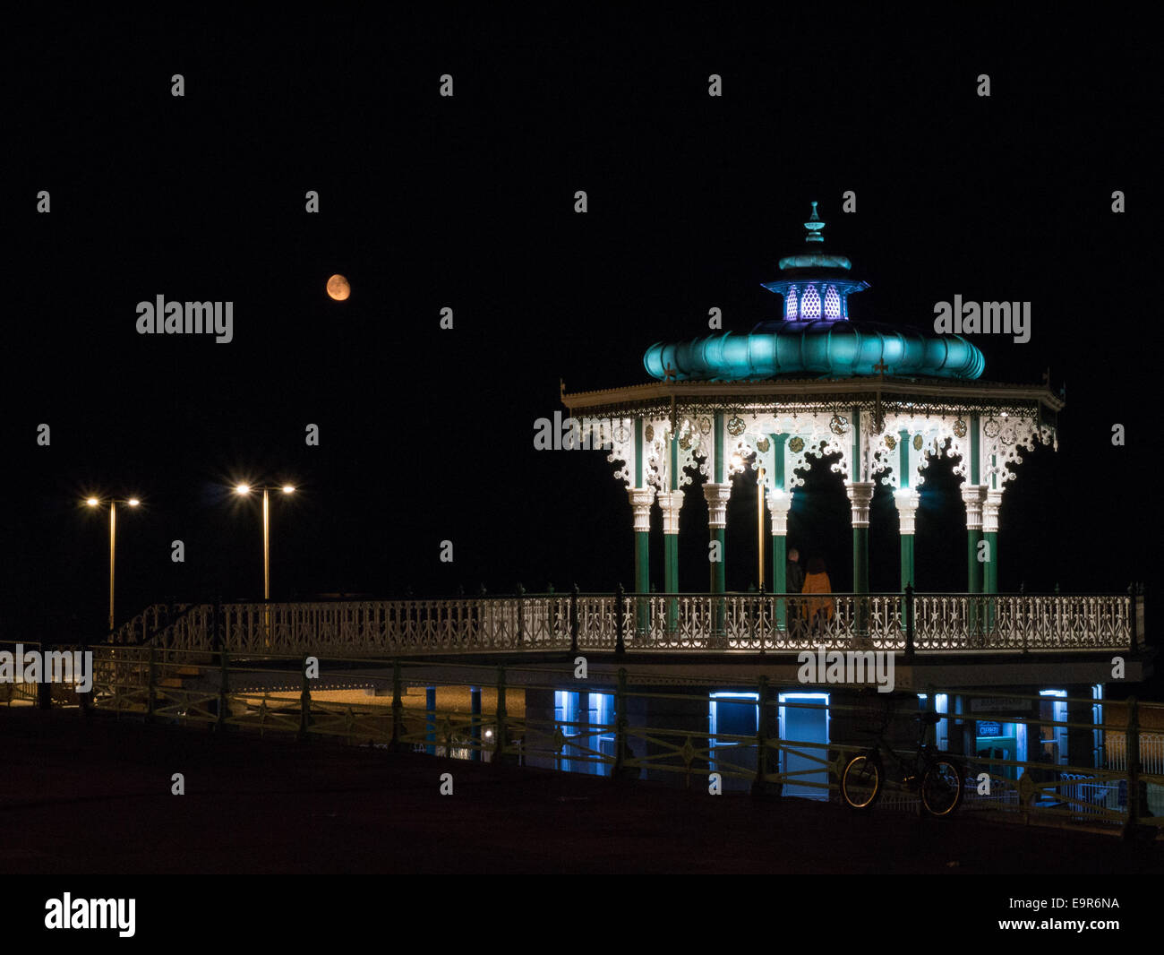 Un couple assiste à Hove Kiosque de nuit avec une lune dans le ciel d'orange Banque D'Images