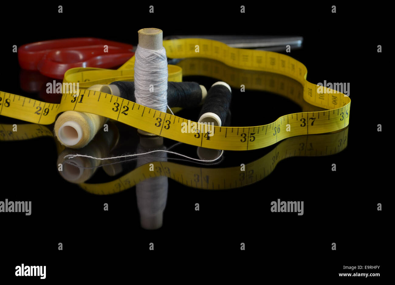 Bobines de fil de coton et ruban à mesurer dans le noir miroir Banque D'Images