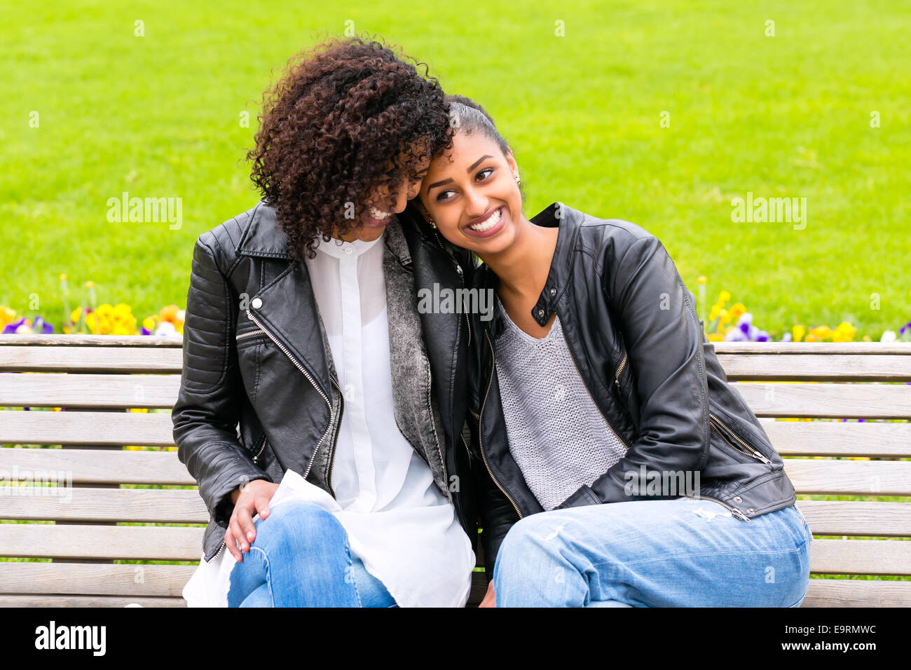 Deux adolescents d'Afrique du Nord friends sitting together on park bench talking Banque D'Images