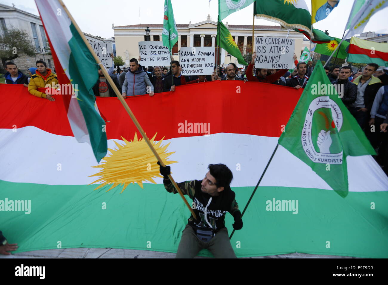 Un manifestant kurde pose avec un petit drapeau kurde devant un grand drapeau kurde. Kurdes vivant en Grèce ont protesté contre les attaques des combattants de l'État islamique sur la ville de Kobane en Syrie. Ils étaient secondés par deux hommes politiques du comité exécutif du Parti de la gauche européenne qui réunit à Athènes pour le week-end. © Michael Debets/Pacific Press/Alamy Live News Banque D'Images