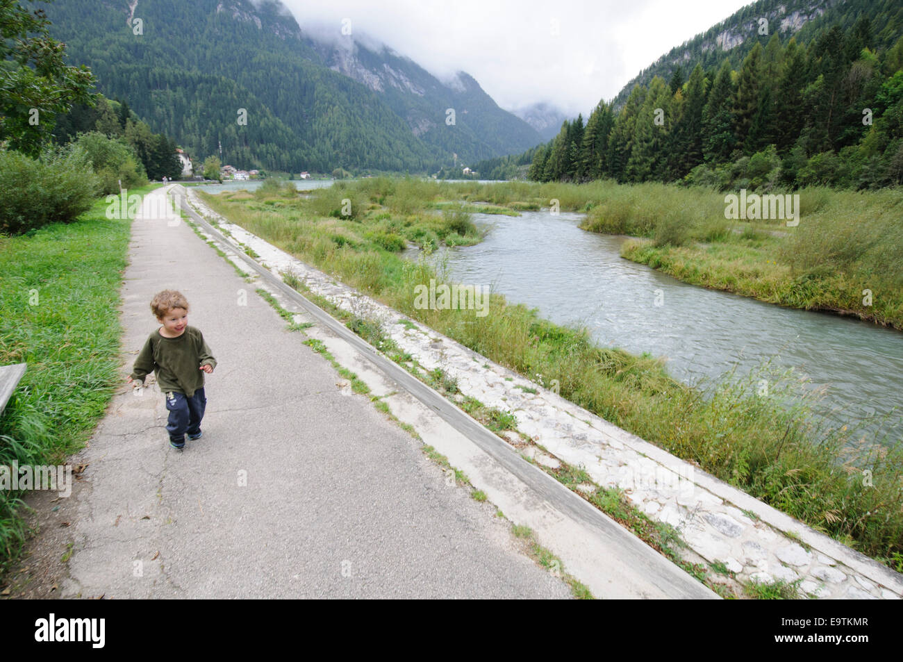 Un jeune enfant en marchant le long d'un ruisseau. Photographié en Italie, Dolomites Banque D'Images