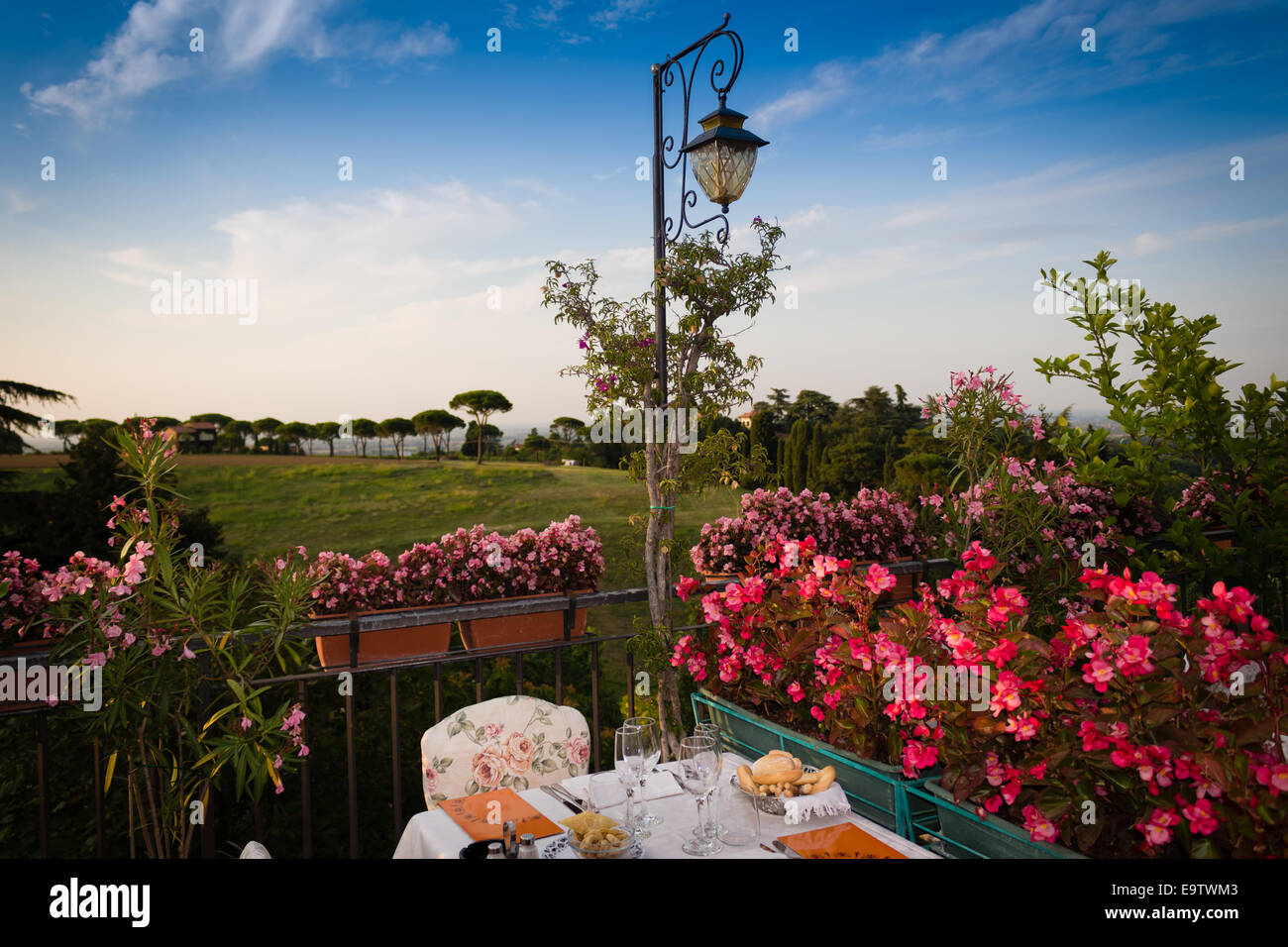 Tables de dîner dans l'élégant restaurant italien de style outdoor sur caillebotis fer parapet sur les collines de Dozza (Bo) en Italie dans une journée ensoleillée d'été : du vrai rouge, jaune et fleurs roses avec des feuilles vertes en pots vert tout autour. Serviettes de table Nappe rose et chic, Banque D'Images Tables de dîner dans l'élégant restaurant italien de style outdoor sur caillebotis fer parapet sur les collines de Dozza (Bo) en Italie dans une journée ensoleillée d'été : du vrai rouge, jaune et fleurs roses avec des feuilles vertes en pots vert tout autour. Serviettes de table Nappe rose et chic, Banque D'Images
