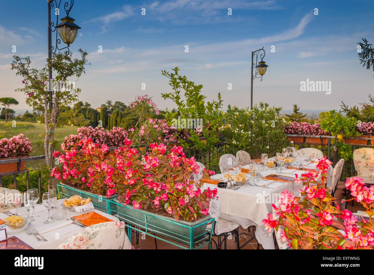 Tables de dîner dans l'élégant restaurant italien de style outdoor sur caillebotis fer parapet sur les collines de Dozza (Bo) en Italie dans une journée ensoleillée d'été : du vrai rouge, jaune et fleurs roses avec des feuilles vertes en pots vert tout autour. Serviettes de table Nappe rose et chic, Banque D'Images Tables de dîner dans l'élégant restaurant italien de style outdoor sur caillebotis fer parapet sur les collines de Dozza (Bo) en Italie dans une journée ensoleillée d'été : du vrai rouge, jaune et fleurs roses avec des feuilles vertes en pots vert tout autour. Serviettes de table Nappe rose et chic, Banque D'Images