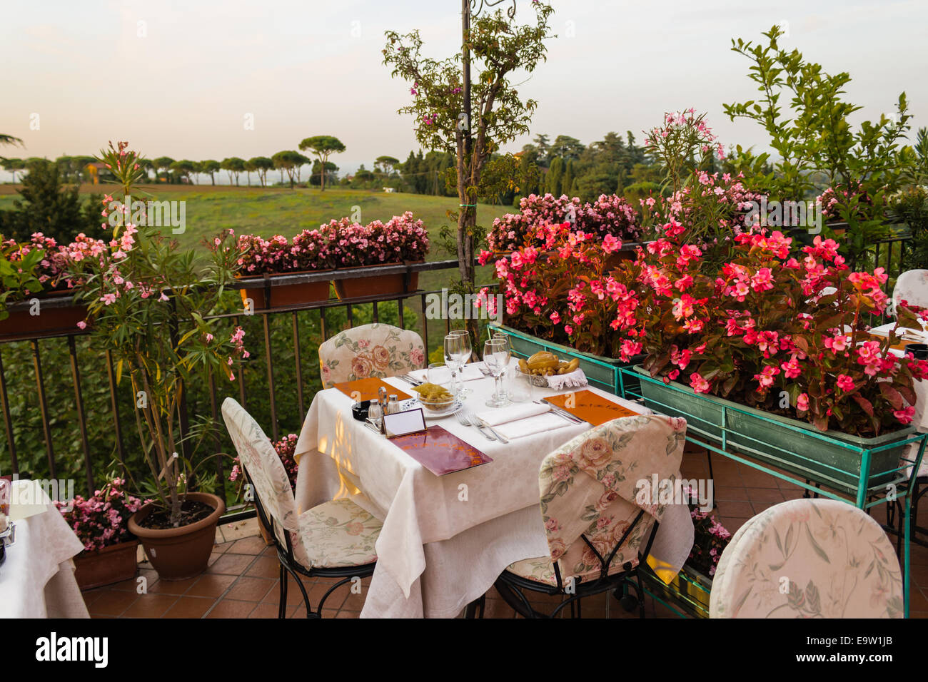 Tables de dîner dans l'élégant restaurant italien de style outdoor sur caillebotis fer parapet sur les collines de Dozza (Bo) en Italie dans une journée ensoleillée d'été : du vrai rouge, jaune et fleurs roses avec des feuilles vertes en pots vert tout autour. Serviettes de table Nappe rose et chic, Banque D'Images Tables de dîner dans l'élégant restaurant italien de style outdoor sur caillebotis fer parapet sur les collines de Dozza (Bo) en Italie dans une journée ensoleillée d'été : du vrai rouge, jaune et fleurs roses avec des feuilles vertes en pots vert tout autour. Serviettes de table Nappe rose et chic, Banque D'Images