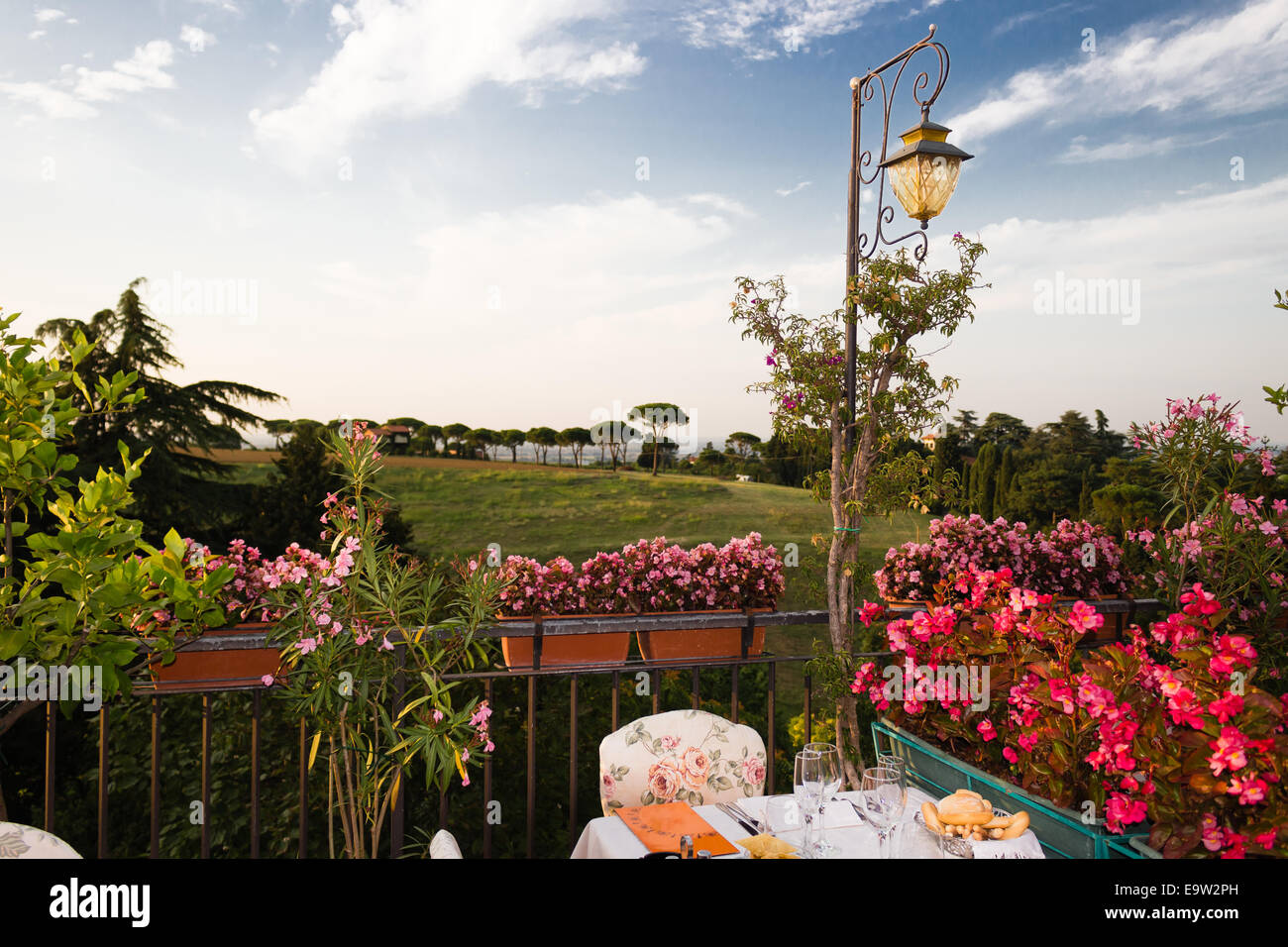 Tables de dîner dans l'élégant restaurant italien de style outdoor sur caillebotis fer parapet sur les collines de Dozza (Bo) en Italie dans une journée ensoleillée d'été : du vrai rouge, jaune et fleurs roses avec des feuilles vertes en pots vert tout autour. Serviettes de table Nappe rose et chic, Banque D'Images Tables de dîner dans l'élégant restaurant italien de style outdoor sur caillebotis fer parapet sur les collines de Dozza (Bo) en Italie dans une journée ensoleillée d'été : du vrai rouge, jaune et fleurs roses avec des feuilles vertes en pots vert tout autour. Serviettes de table Nappe rose et chic, Banque D'Images