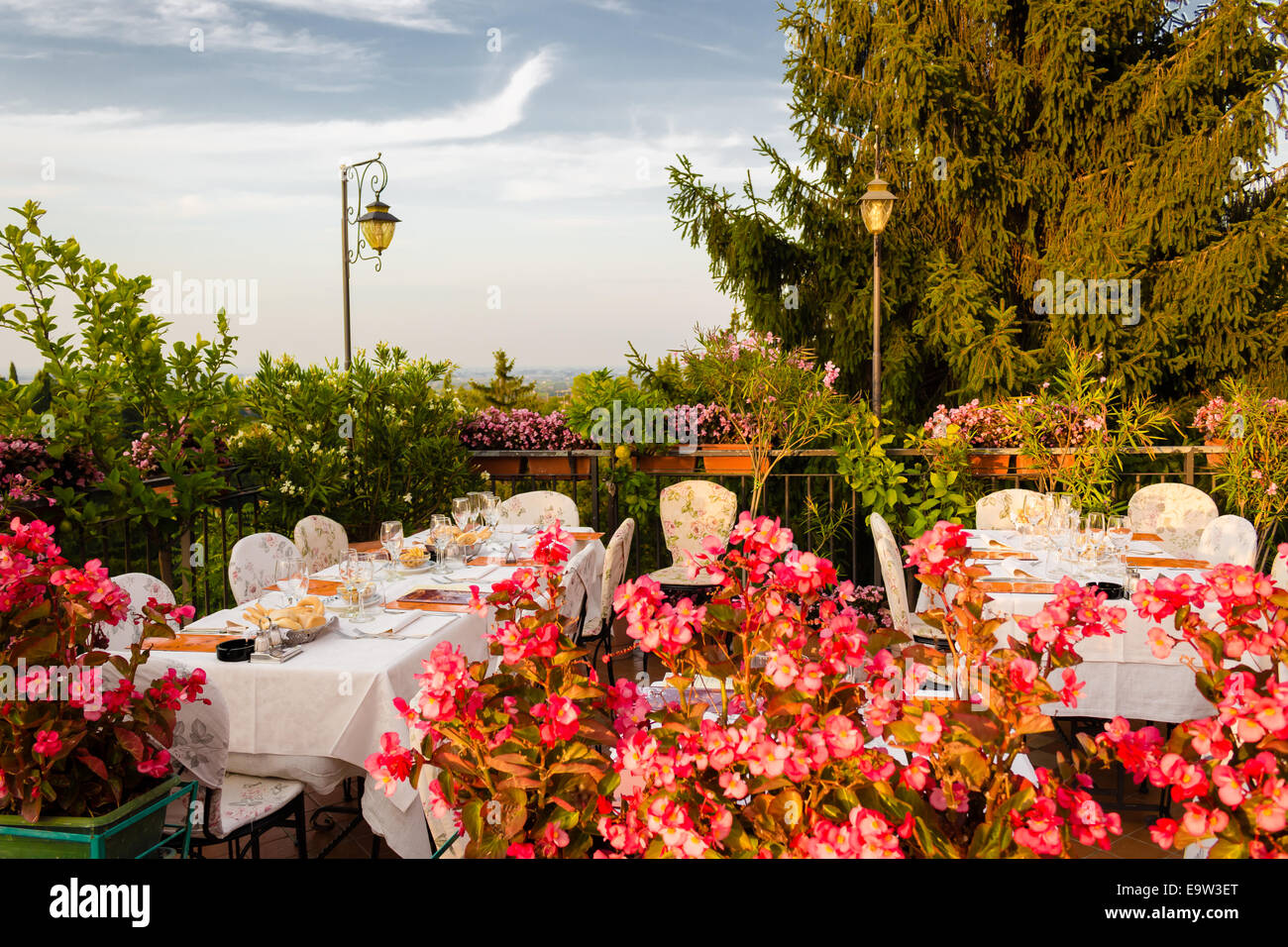 Tables de dîner dans l'élégant restaurant italien de style outdoor sur caillebotis fer parapet sur les collines de Dozza (Bo) en Italie dans une journée ensoleillée d'été : du vrai rouge, jaune et fleurs roses avec des feuilles vertes en pots vert tout autour. Serviettes de table Nappe rose et chic, Banque D'Images Tables de dîner dans l'élégant restaurant italien de style outdoor sur caillebotis fer parapet sur les collines de Dozza (Bo) en Italie dans une journée ensoleillée d'été : du vrai rouge, jaune et fleurs roses avec des feuilles vertes en pots vert tout autour. Serviettes de table Nappe rose et chic, Banque D'Images