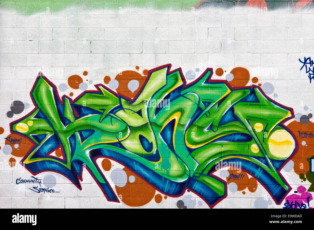 Un cadre coloré vert, bleu et orange peinture graffiti sur un mur en brique blanche Banque D'Images