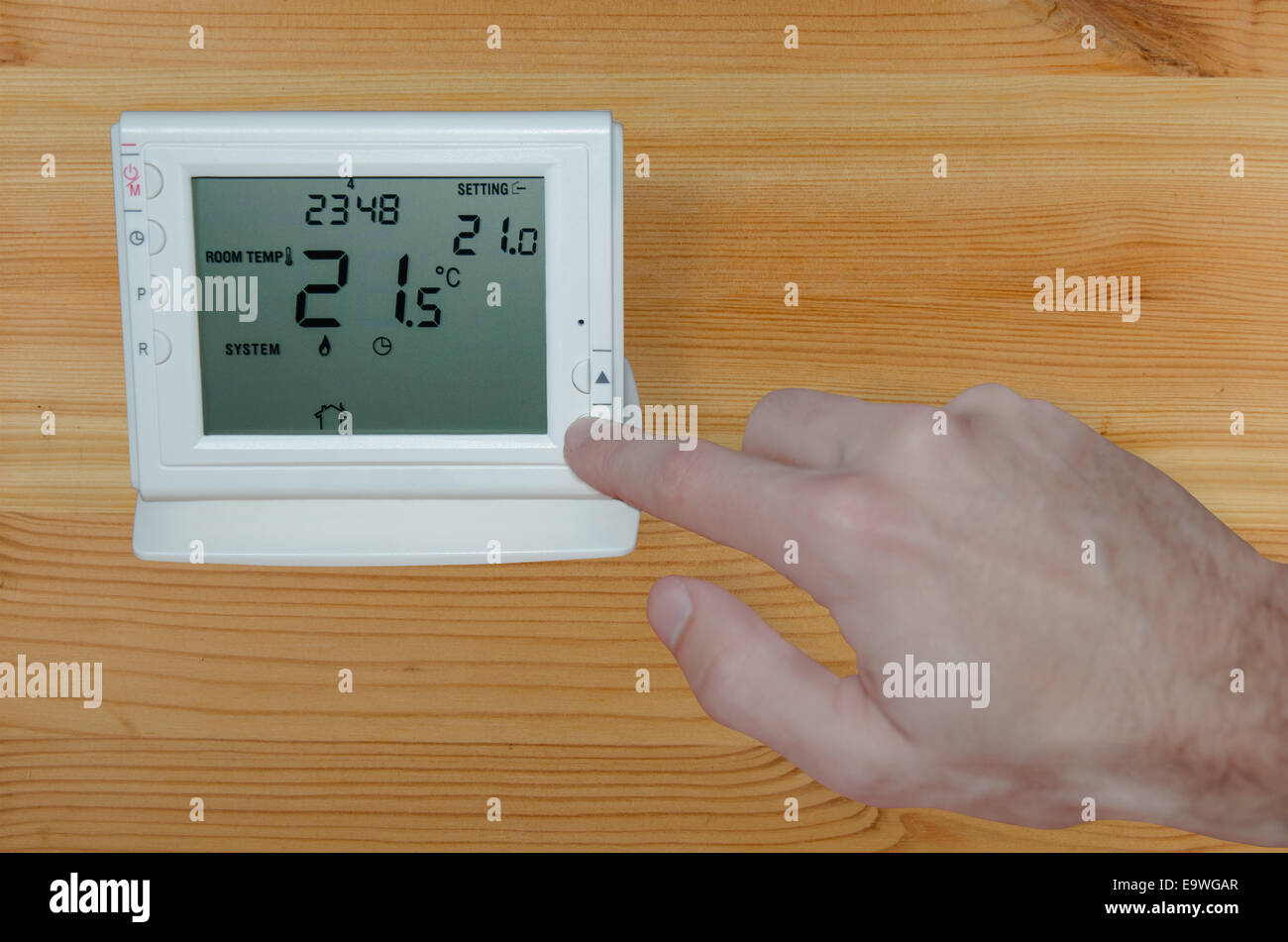 Réglage de la température ambiante dans la maison avec la main pour un thermostat sans fil Banque D'Images