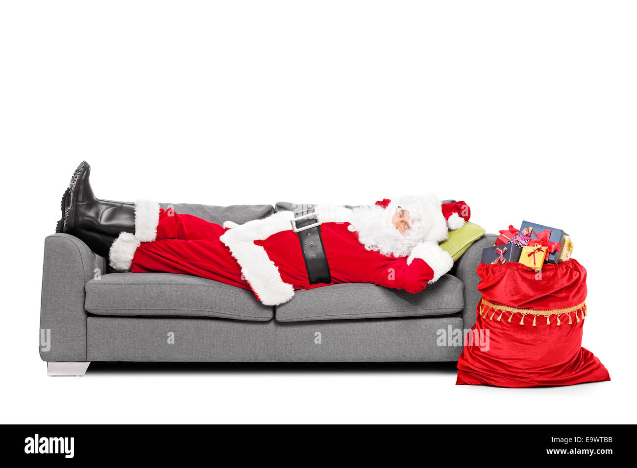 Santa dormir sur le canapé avec un sac de cadeaux à côté de lui isolé sur fond blanc Banque D'Images