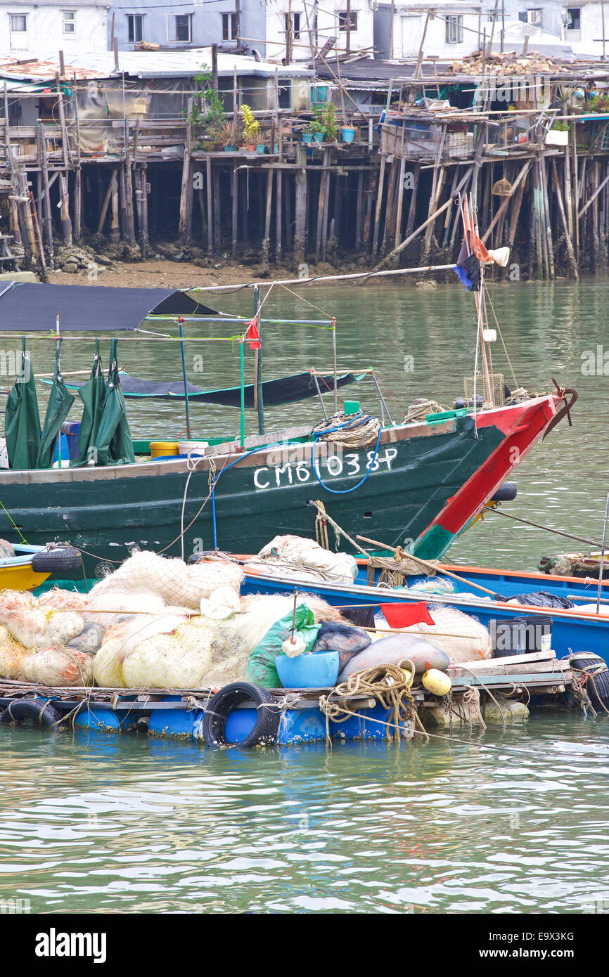 Bateau de pêche chinois en bois avec le Tai O Village de maisons sur pilotis à l'arrière-plan, l'île de Lantau, à Hong Kong. Banque D'Images