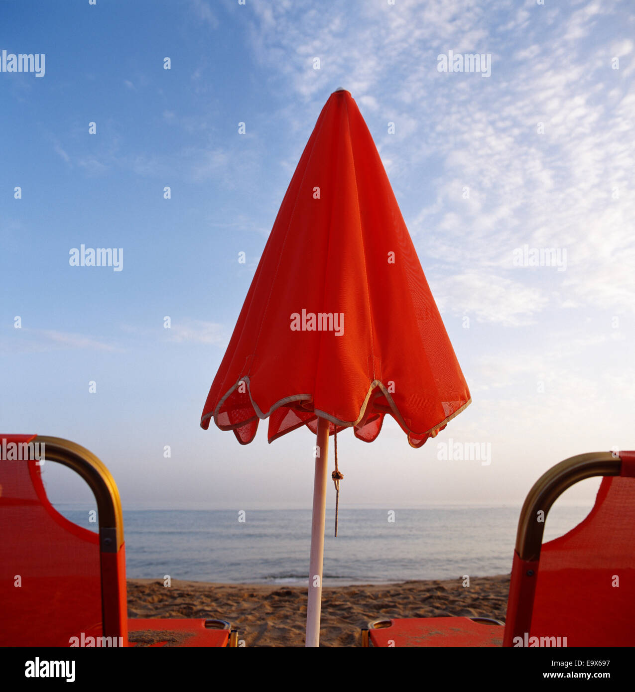 Orange deux chaises de plage et parasol fermé sur une plage de sable Banque D'Images