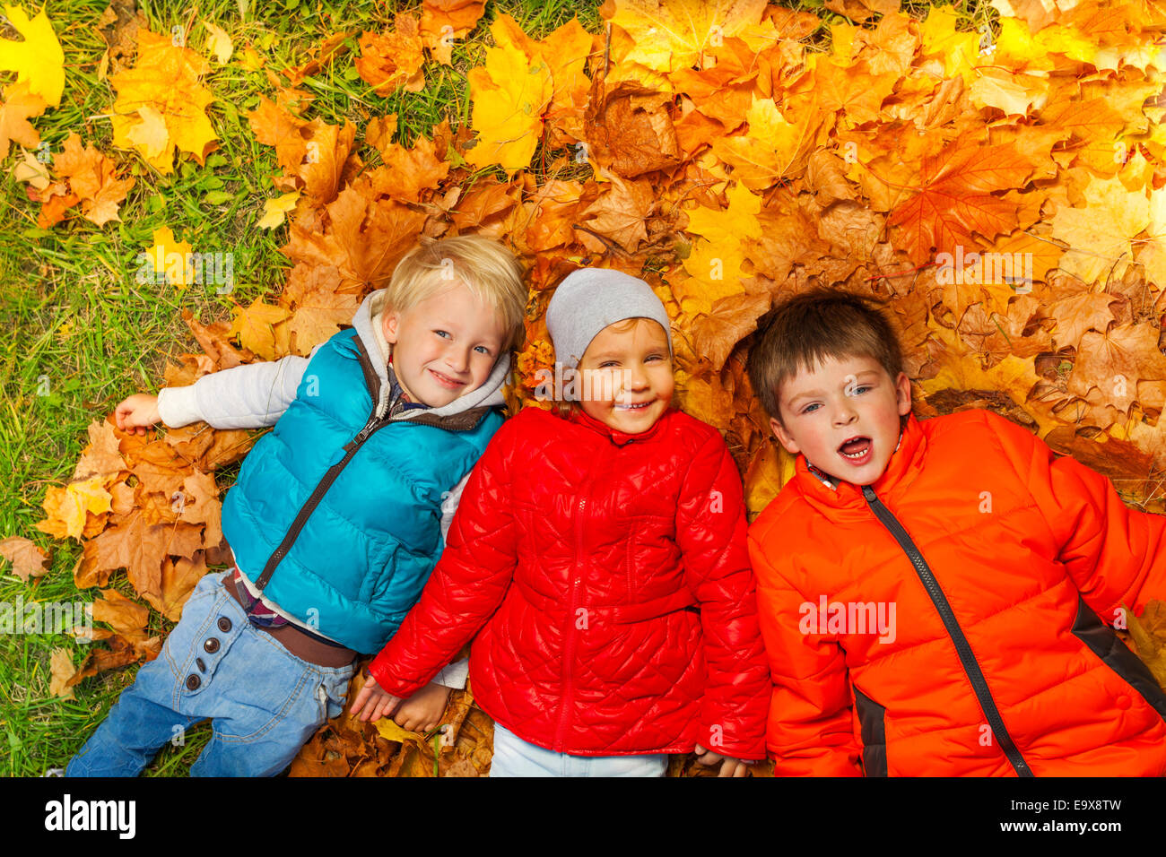 Happy kids fixant ensemble sur les feuilles d'automne Banque D'Images