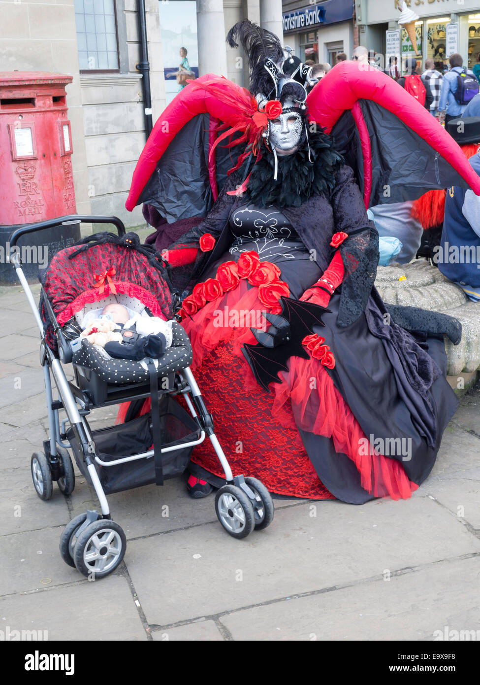 Une femme dans un costume de chauve-souris gonflable assis avec une poupée habillée en Goths au Whitby Goth semaine fin automne 2014 Banque D'Images