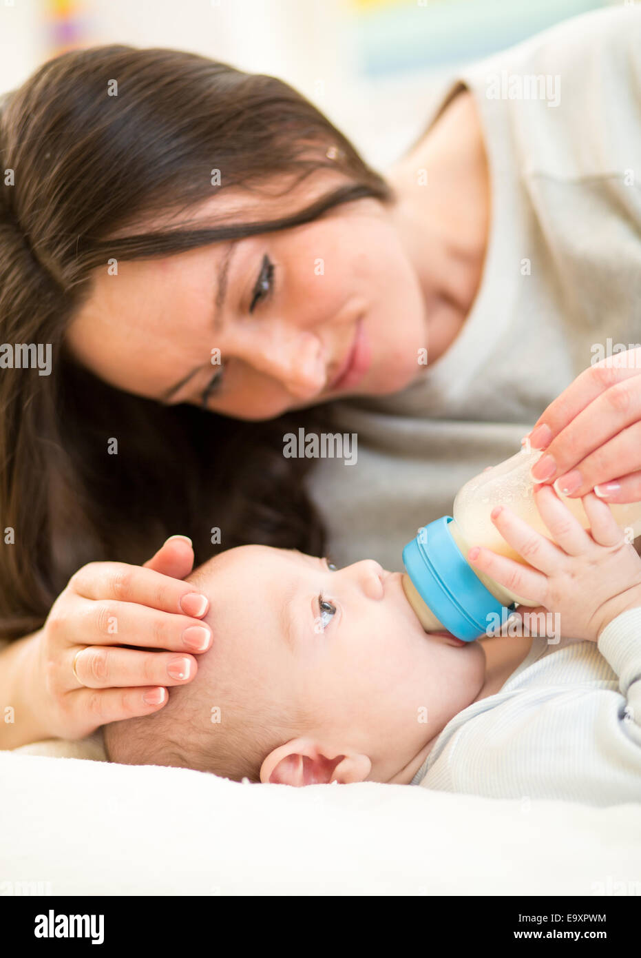 La mère à la maison nourrir bébé avec une bouteille de lait Banque D'Images