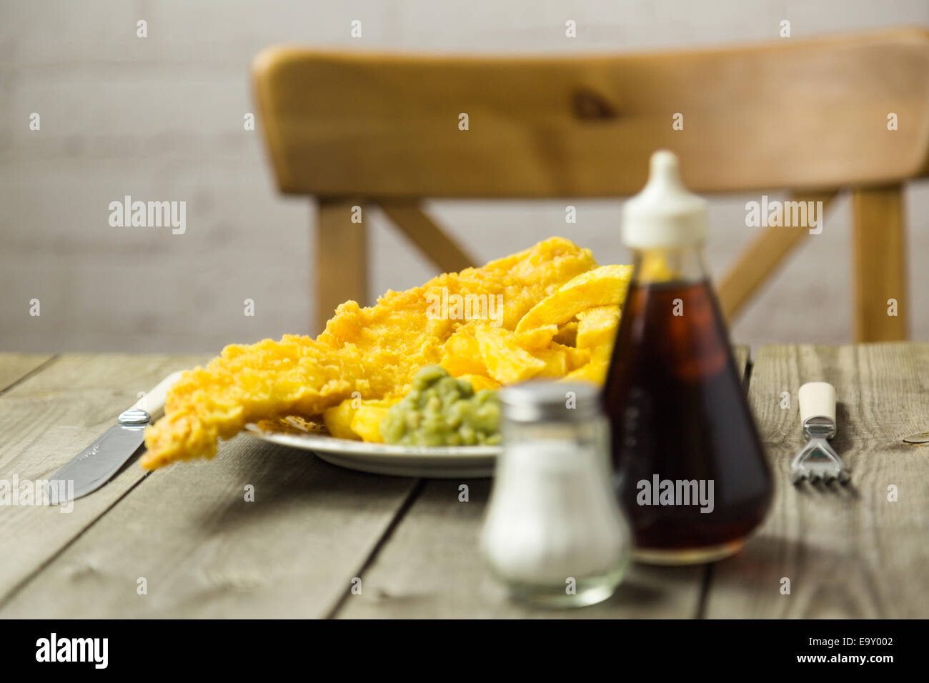 Repas à emporter britannique traditionnel de poisson et frites avec petits pois sur une plaque de papier journal Banque D'Images