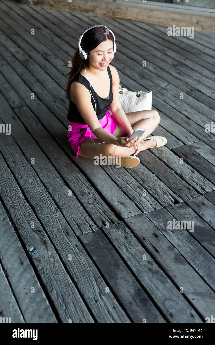 Une jeune femme asiatique en utilisant son périphérique mobile Banque D'Images