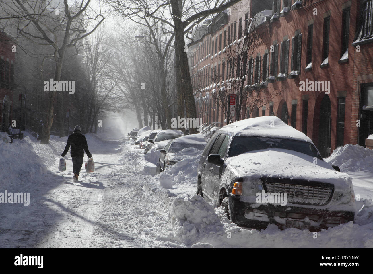 Homme portant des sacs de shopping lors d'une forte tempête de neige à Brooklyn New York Banque D'Images