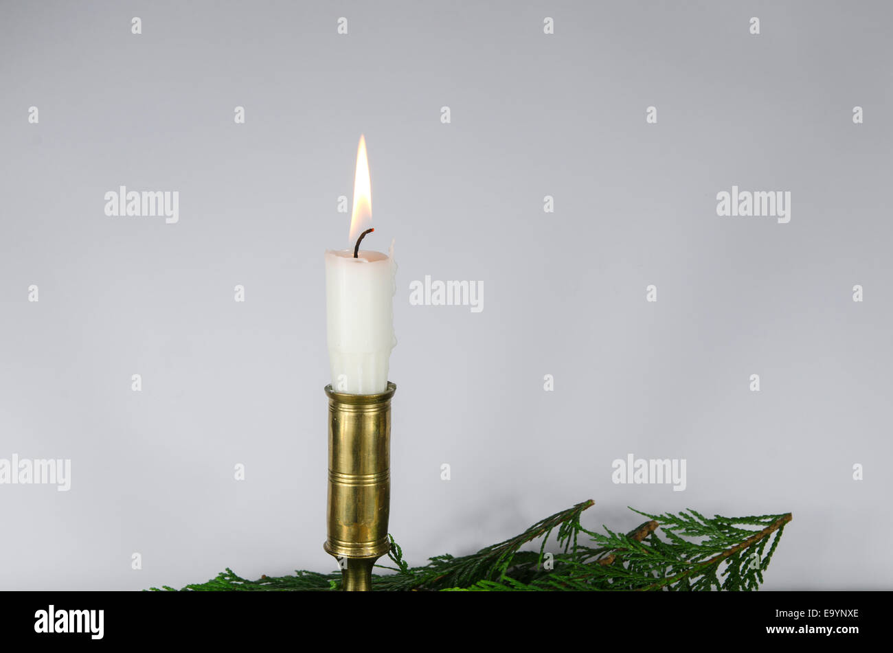 Une combustion bougie blanche dans un chandelier de bronze à un mur blanc Banque D'Images