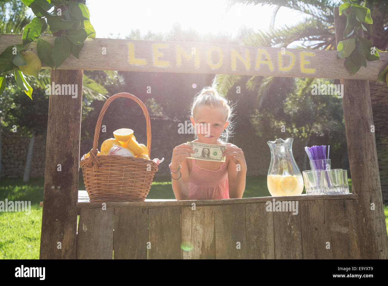 Portrait de jeune fille sur lemonade stand holding up one dollar bill Banque D'Images
