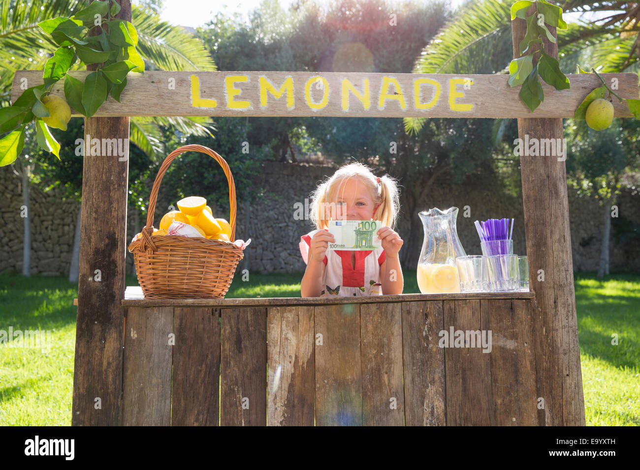 Portrait de jeune fille sur lemonade stand holding up cent euro note Banque D'Images