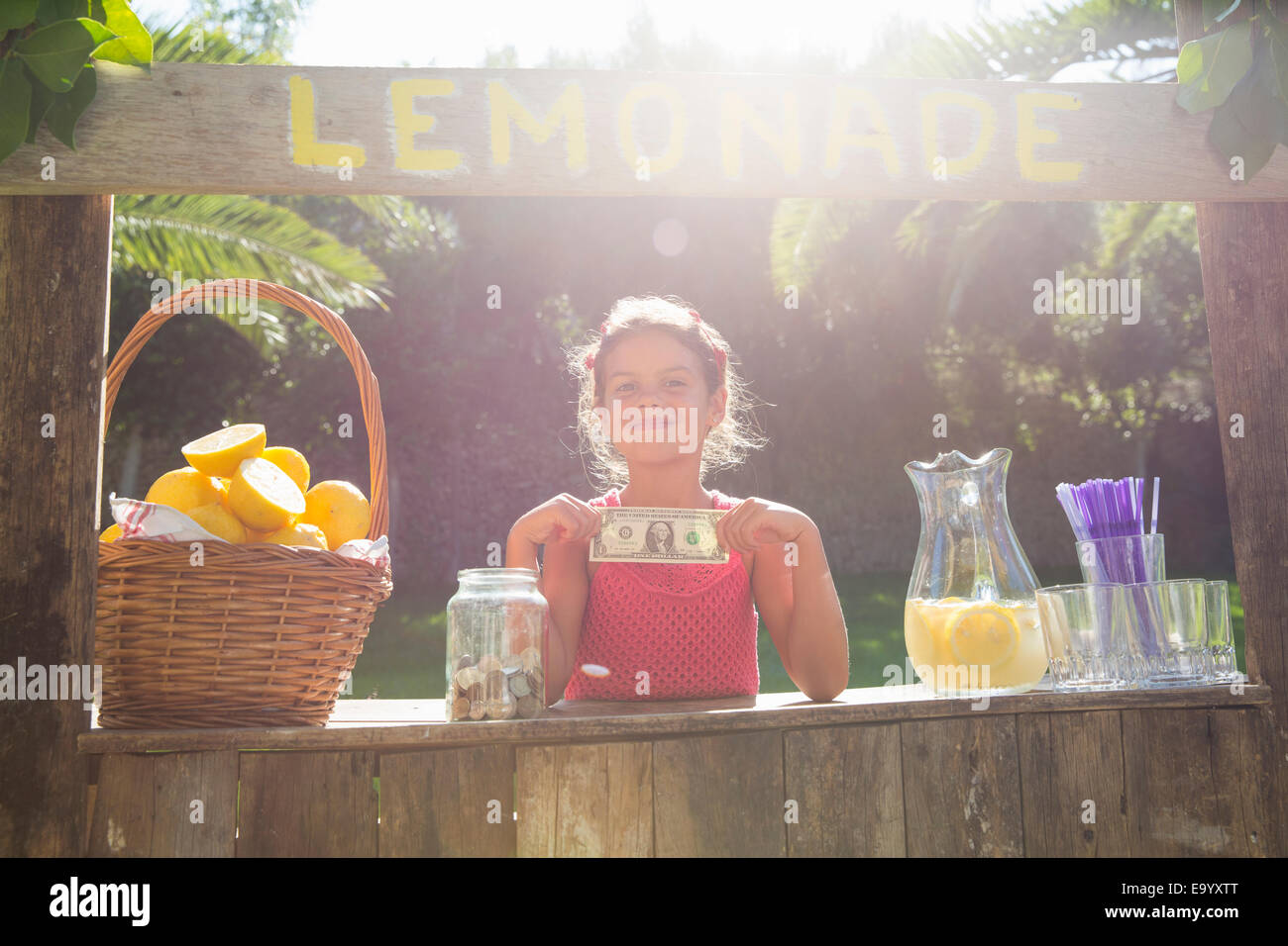 Portrait de jeune fille fière sur lemonade stand holding up one dollar bill Banque D'Images