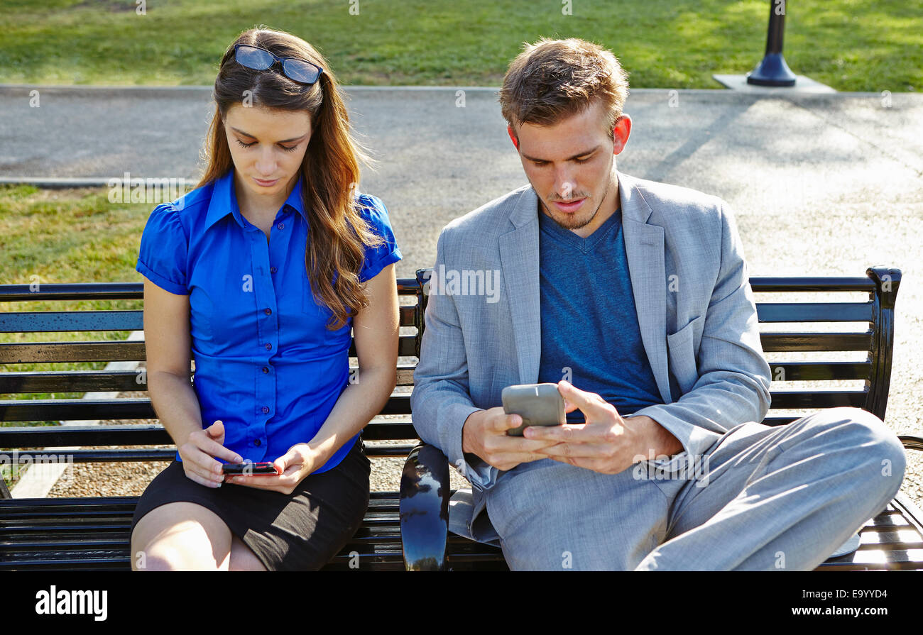 Businessman and woman using smartphone in park Banque D'Images