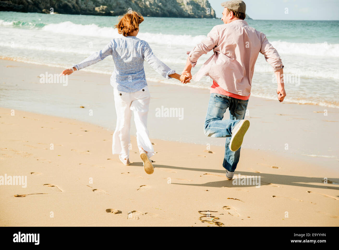 Young couple holding hands running on beach, Camaret-sur-mer, Bretagne, France Banque D'Images