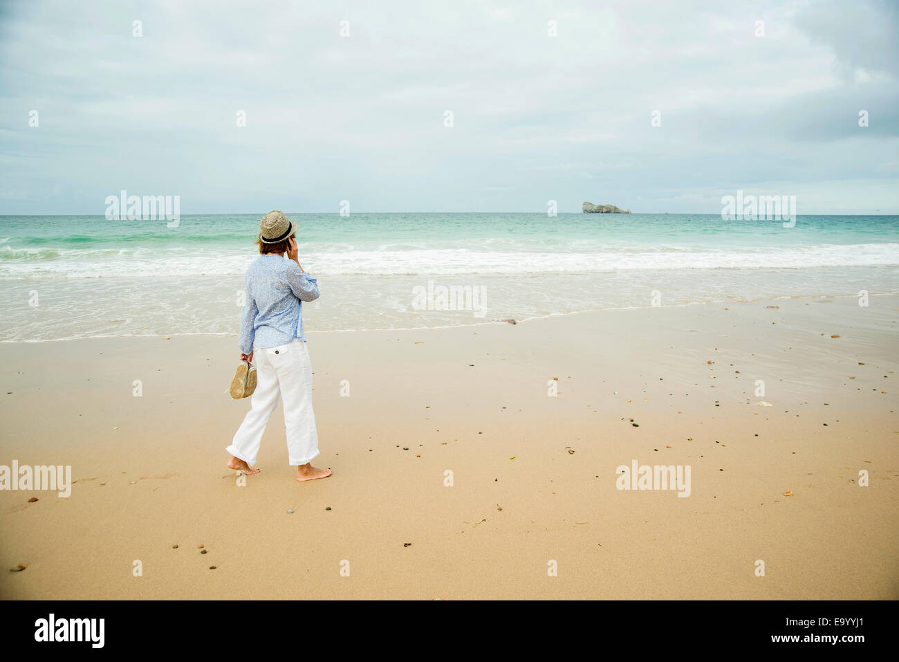 Young woman strolling on beach chatting on smartphone, Camaret-sur-mer, Bretagne, France Banque D'Images