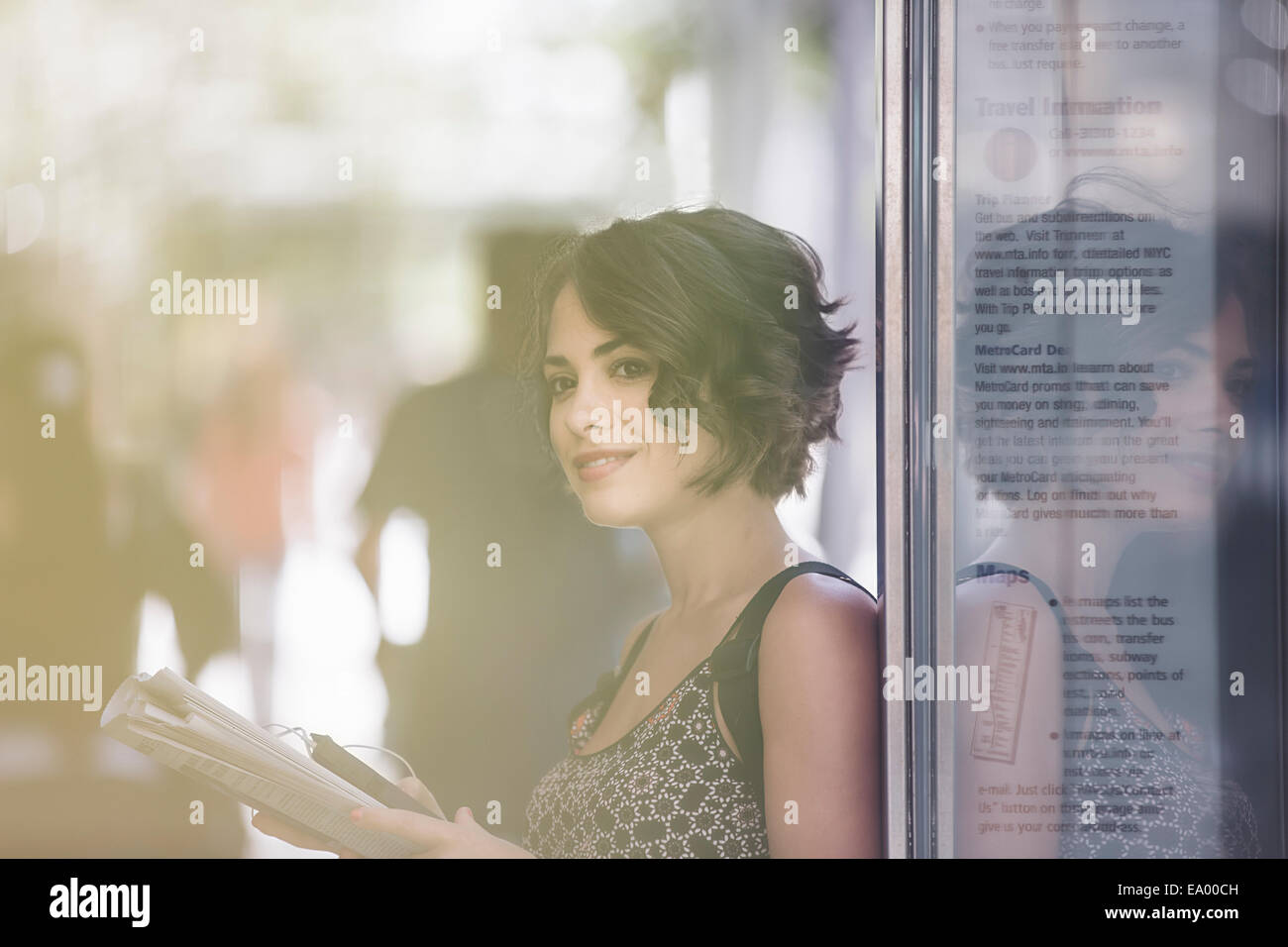 Jeune femme à l'arrêt de bus lisant le journal, en attente de bus, New York, États-Unis Banque D'Images