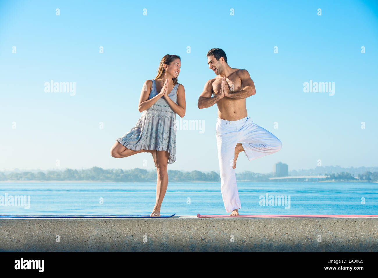 Young man and woman practicing yoga position sur une jetée à Pacific Beach, San Diego, California, USA Banque D'Images