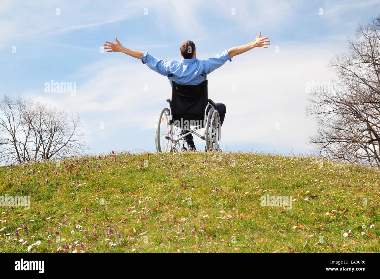 Heureux utilisateur de fauteuil roulant sur une colline verte Banque D'Images