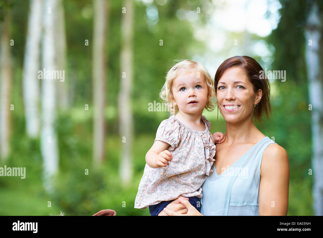 Portrait of mid adult woman and toddler daughter in garden Banque D'Images