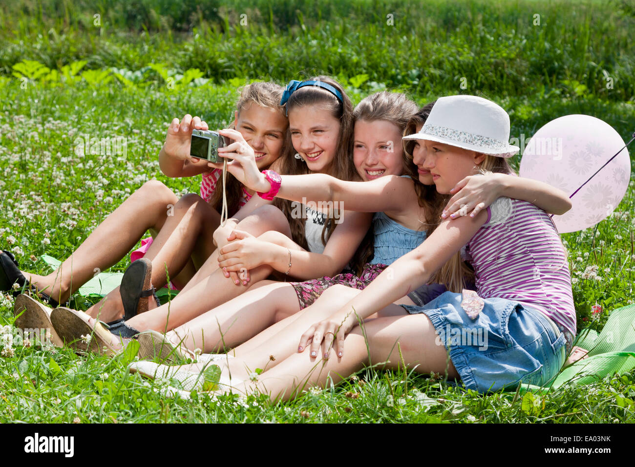 Belles filles de prendre une photographie de l'herbe dans le parc de la ville à l'extérieur Banque D'Images