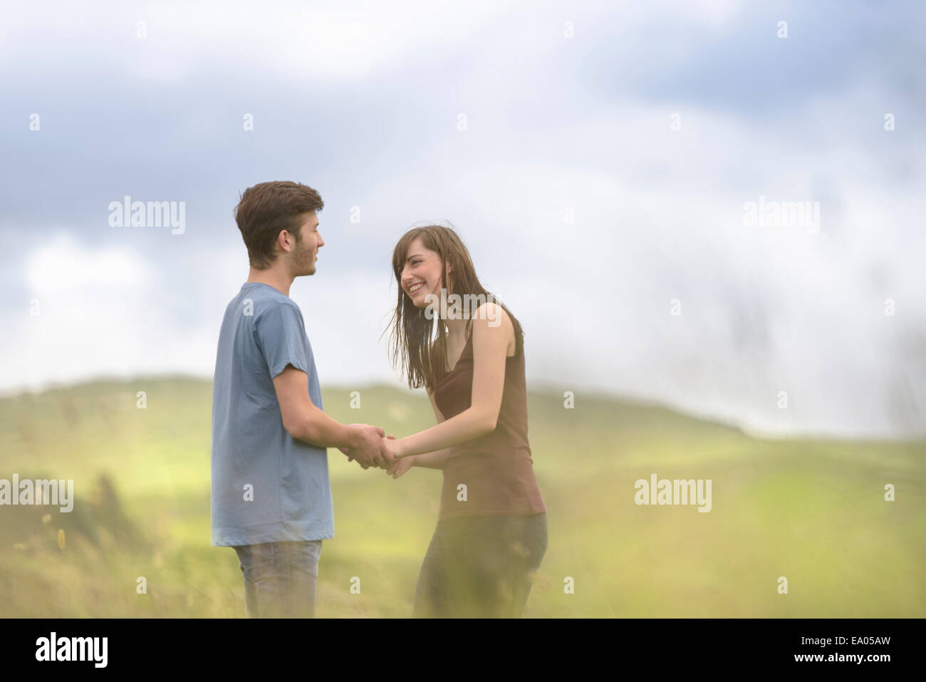 Young couple holding hands ensemble dans le pré sous ciel clair Banque D'Images