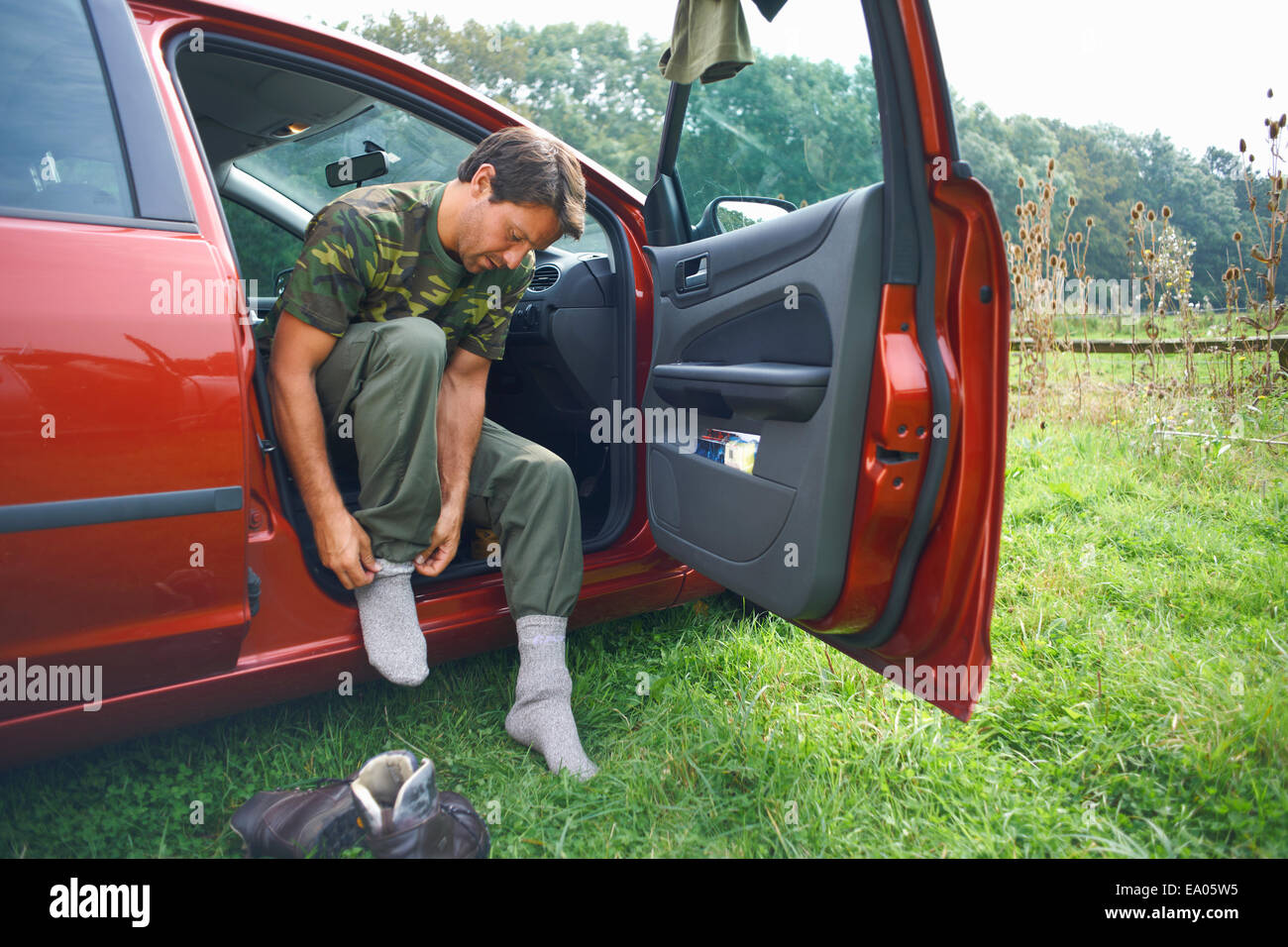 Man sitting in car mettre des chaussettes sur Banque D'Images