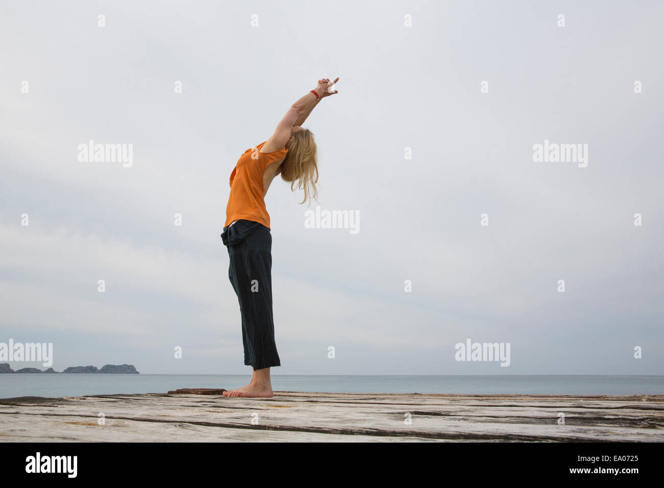 Mid adult woman qui remonte à la pratique du yoga sur la mer en bois pier Banque D'Images