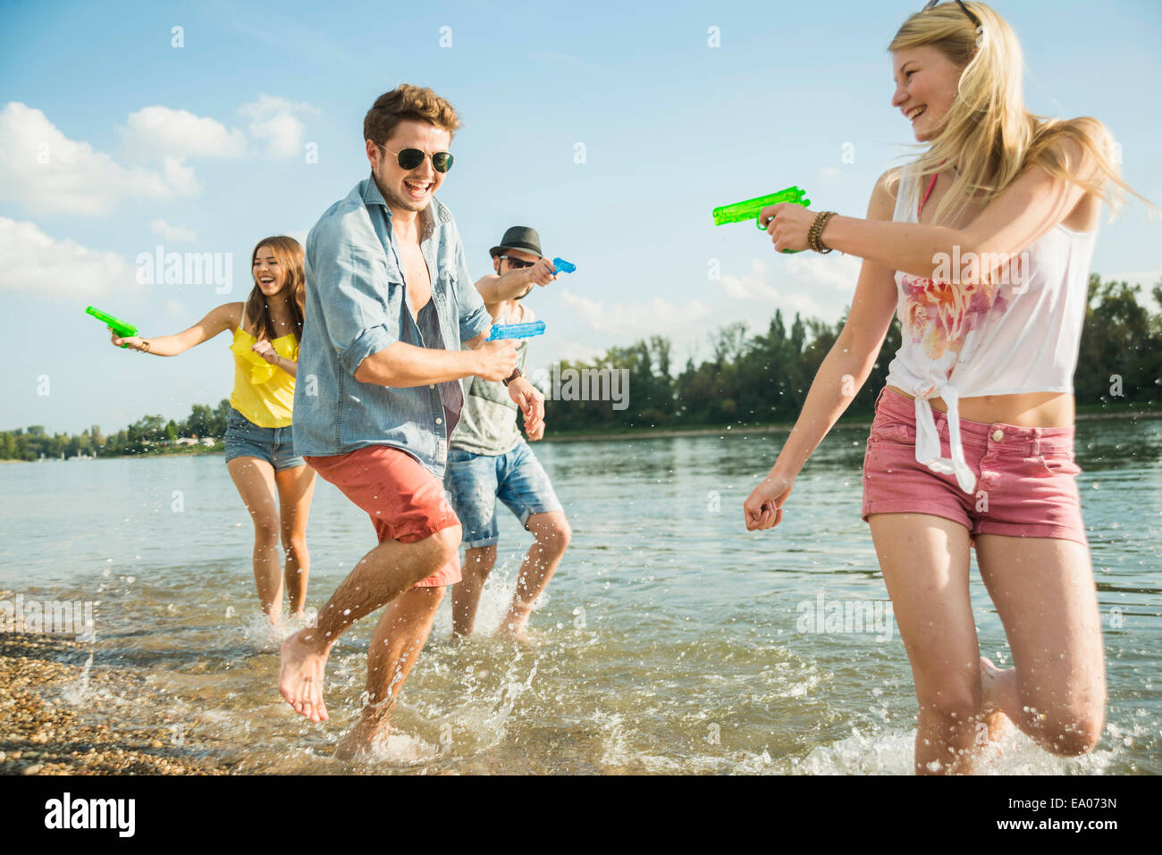 Les amis de jouer avec les pistolets à eau dans le lac Banque D'Images