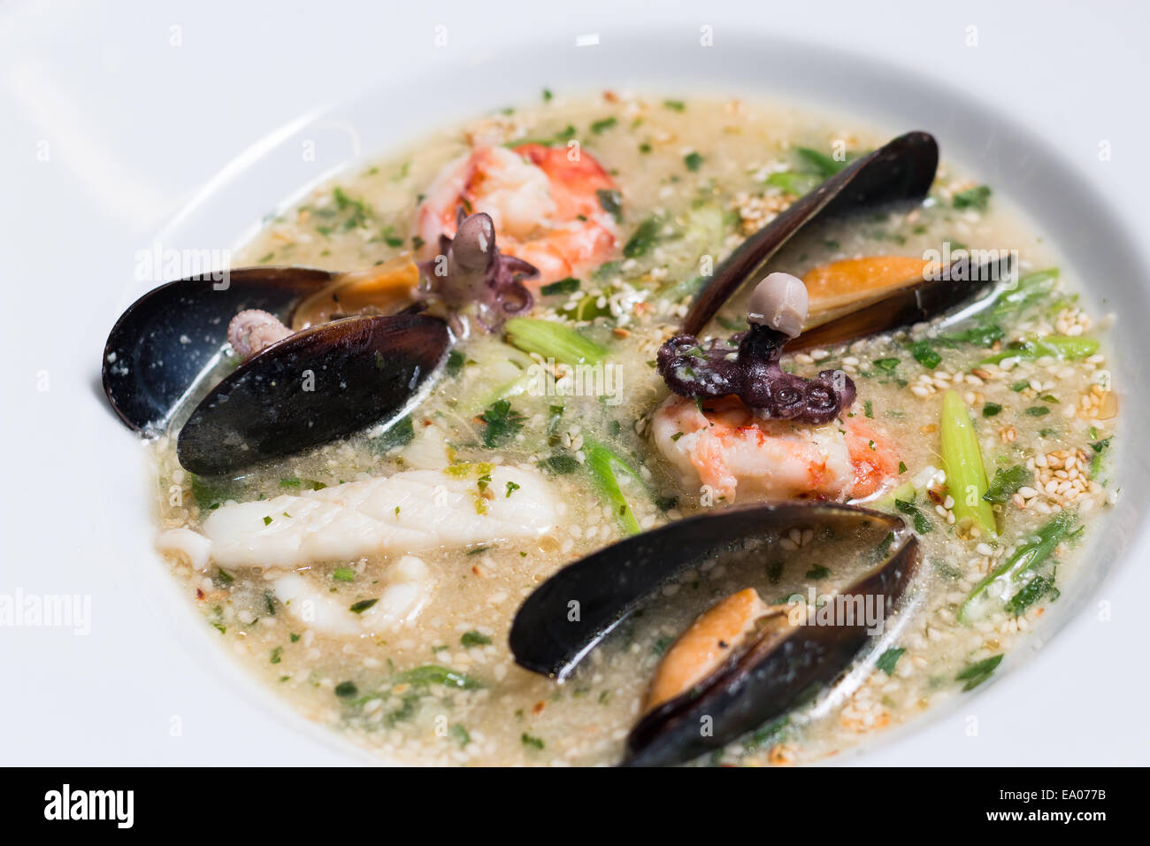 Soupe de poulpe avec des moules dans une assiette blanche Banque D'Images