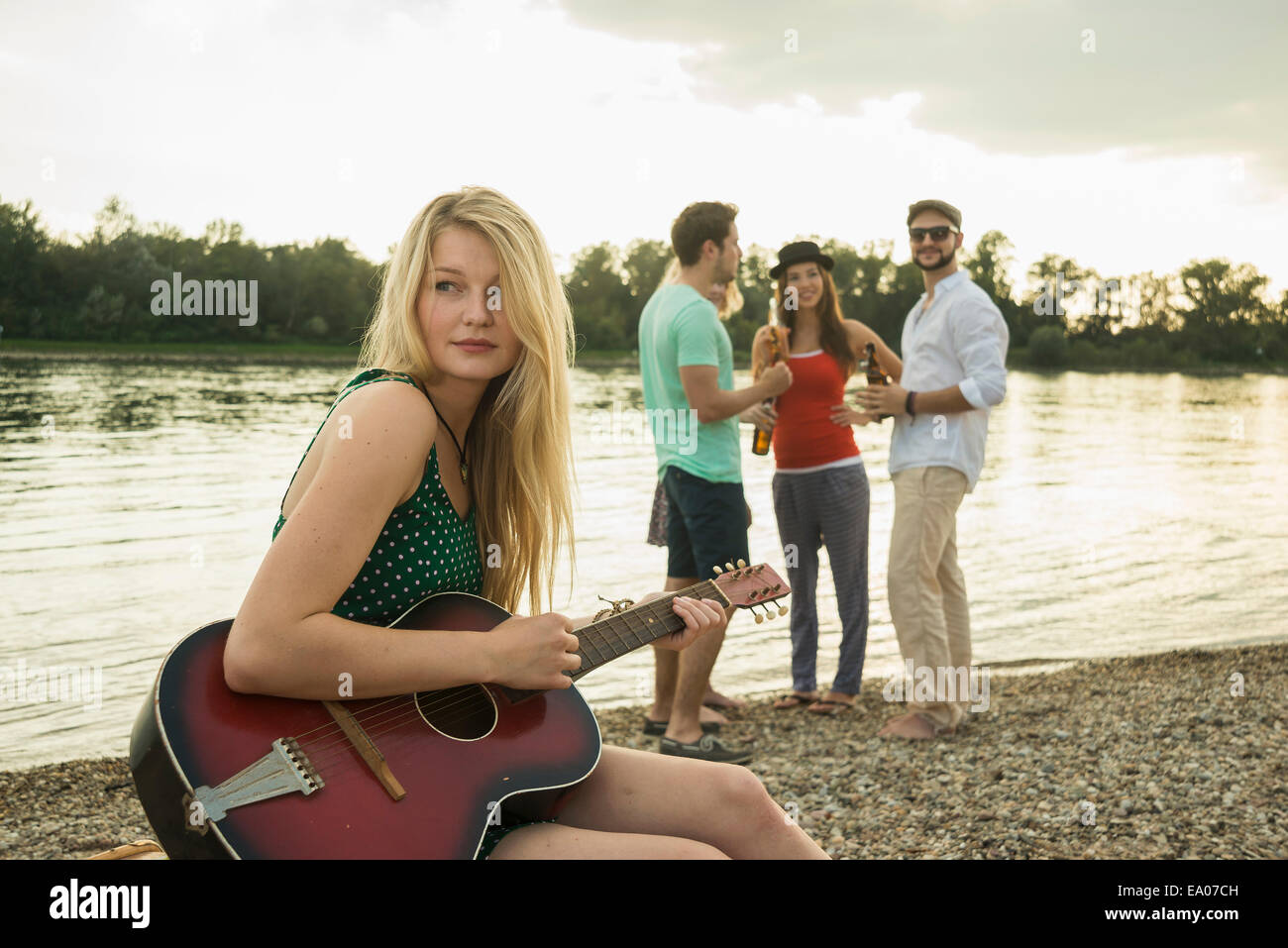 Jeune femme jouant de la guitare par lake Banque D'Images