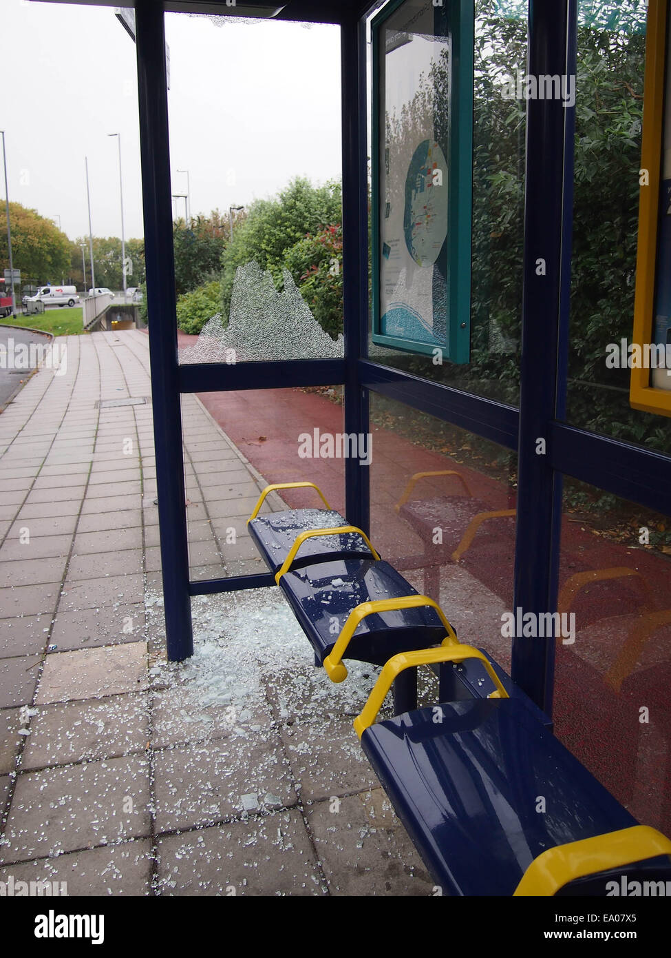 Un abri d'autobus urbain avec une vitre cassée et le verre se trouvant autour de l'étage Banque D'Images