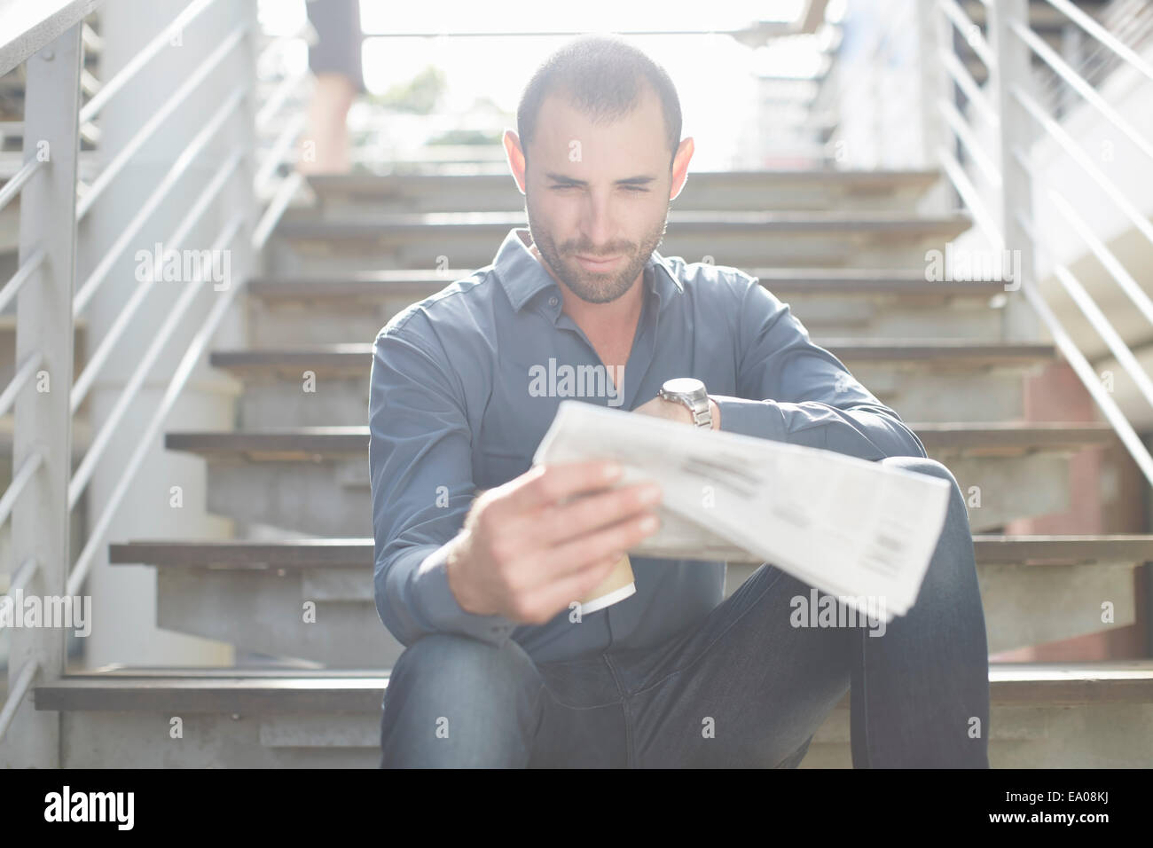 La lecture des journaux d'affaires on staircase Banque D'Images