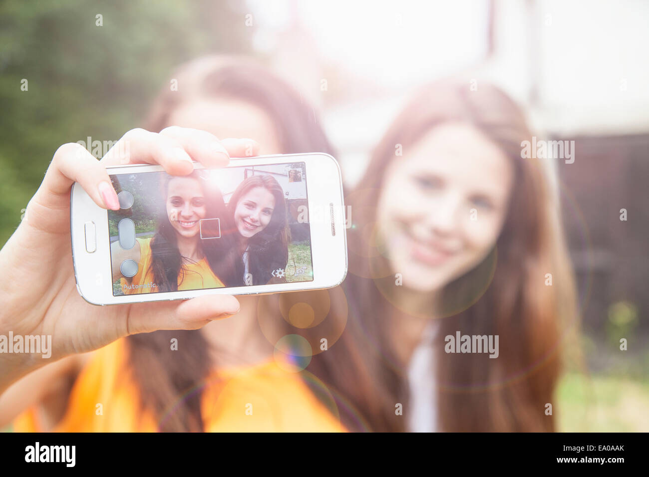 Les jeunes femmes en tenant sur smartphone selfies Banque D'Images