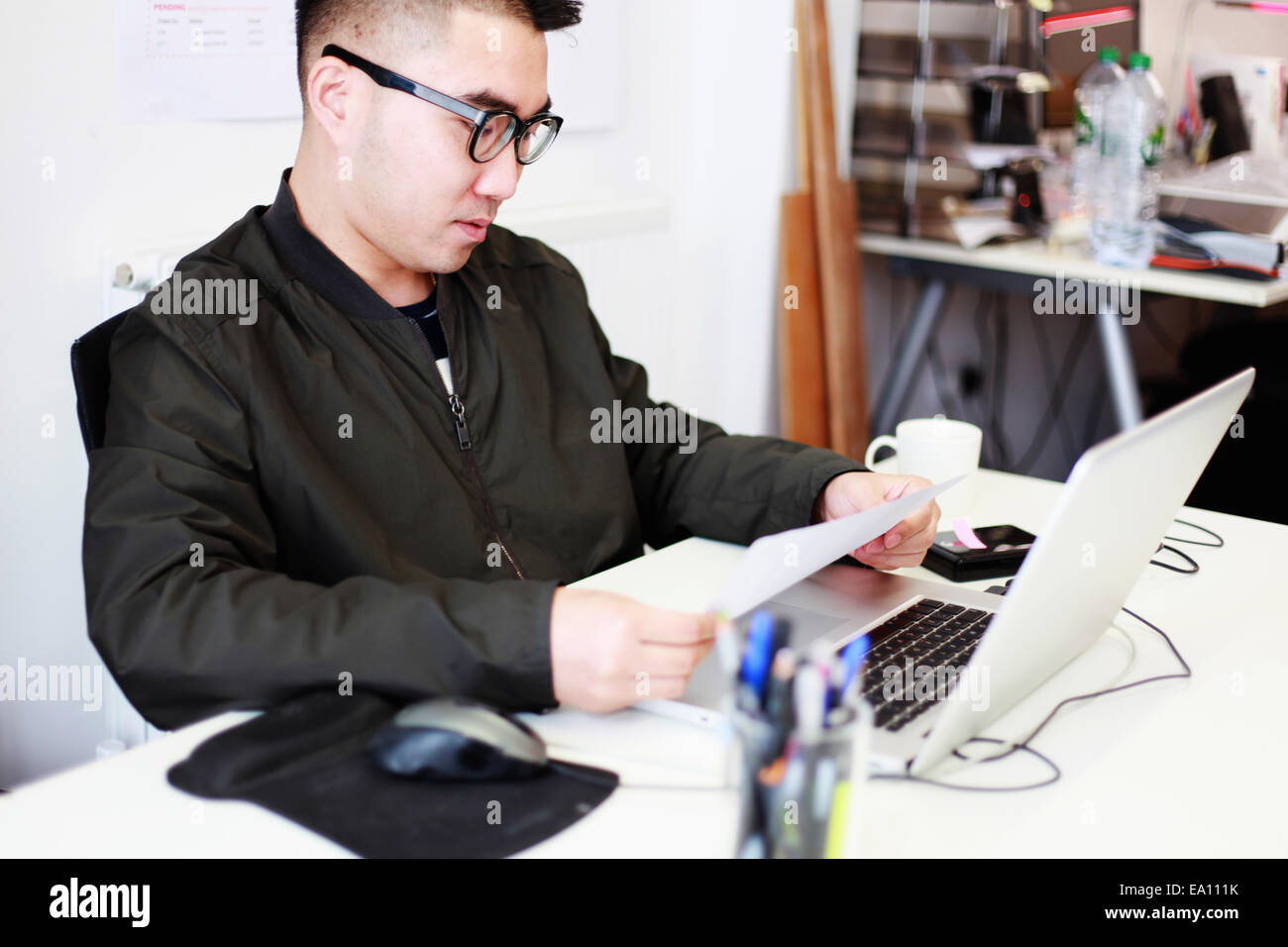 Architect reading paperwork at office desk Banque D'Images