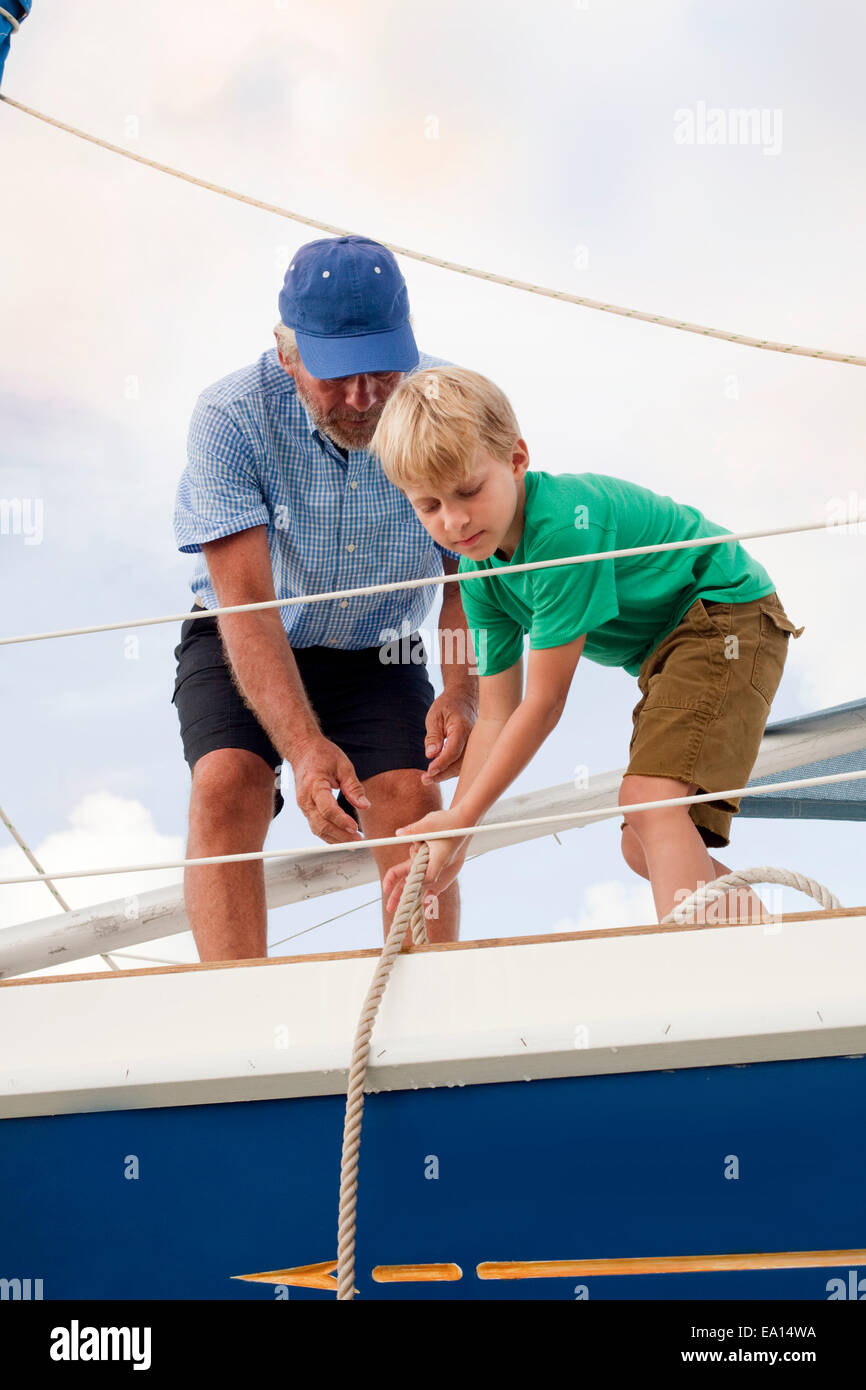 Boy aider grand-père tirez des cordes sur voilier Banque D'Images