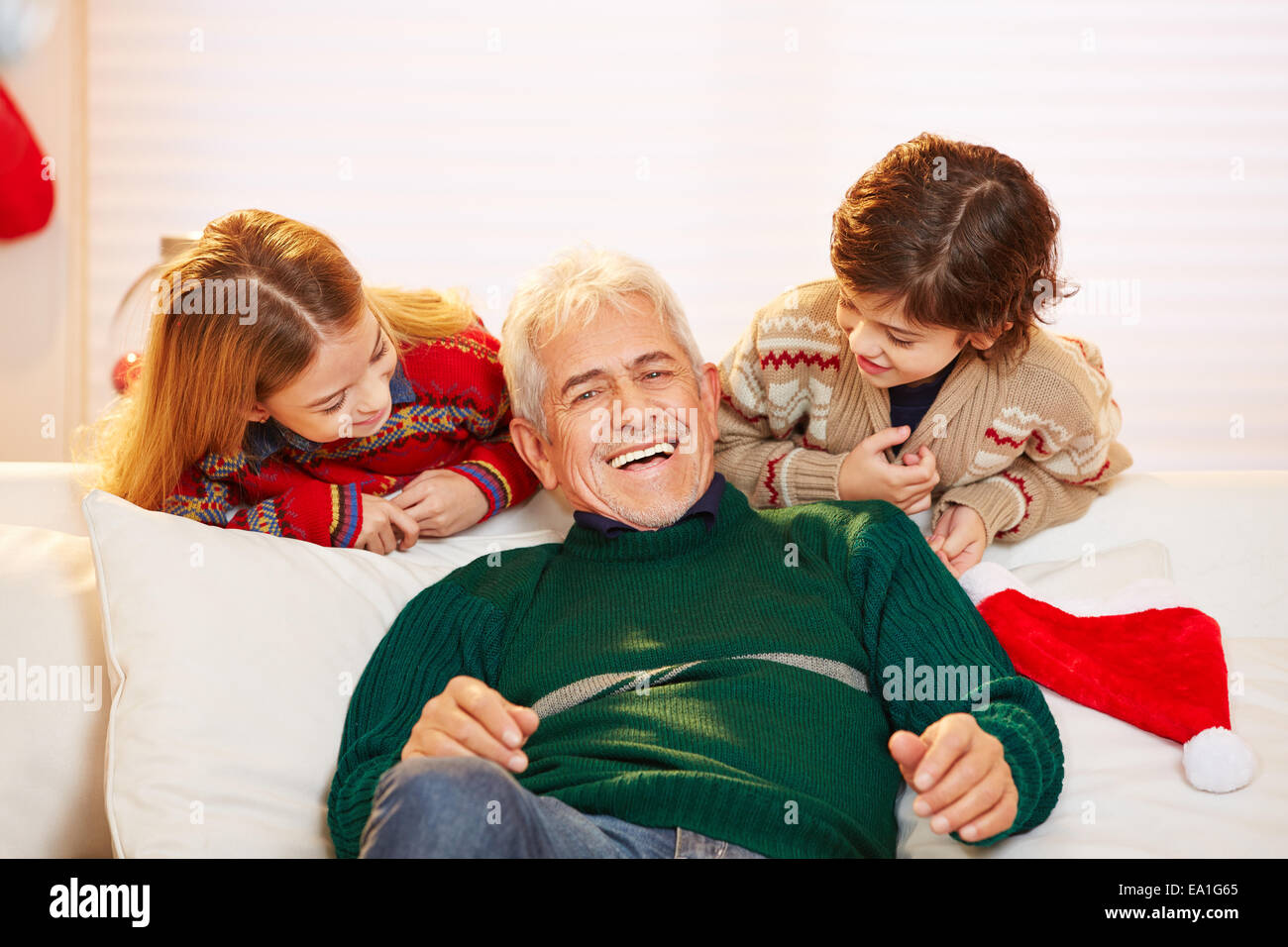 Heureux grand-père assis avec petits-enfants à Noël sur le canapé Banque D'Images