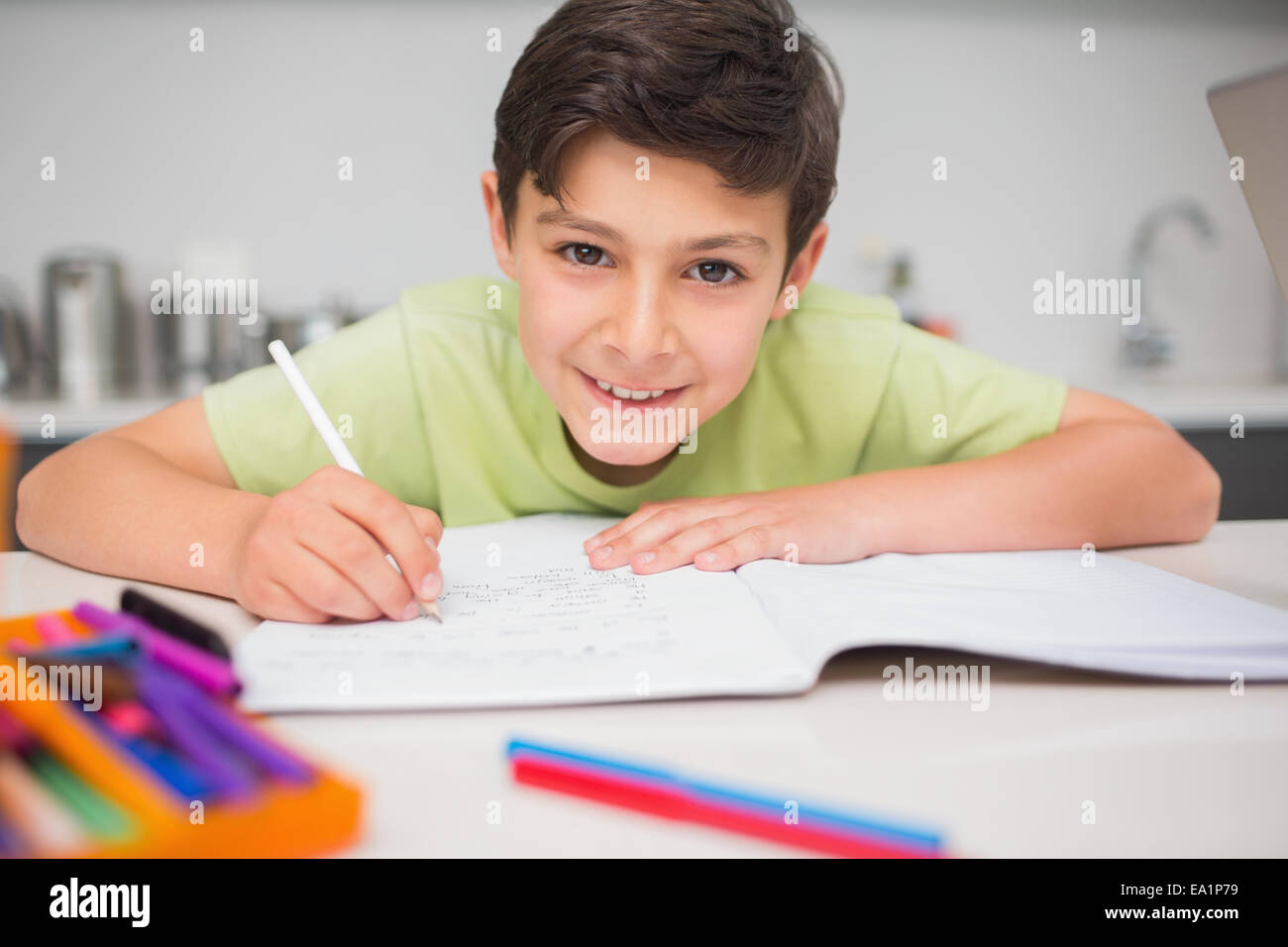 Smiling boy doing Homework in kitchen Banque D'Images