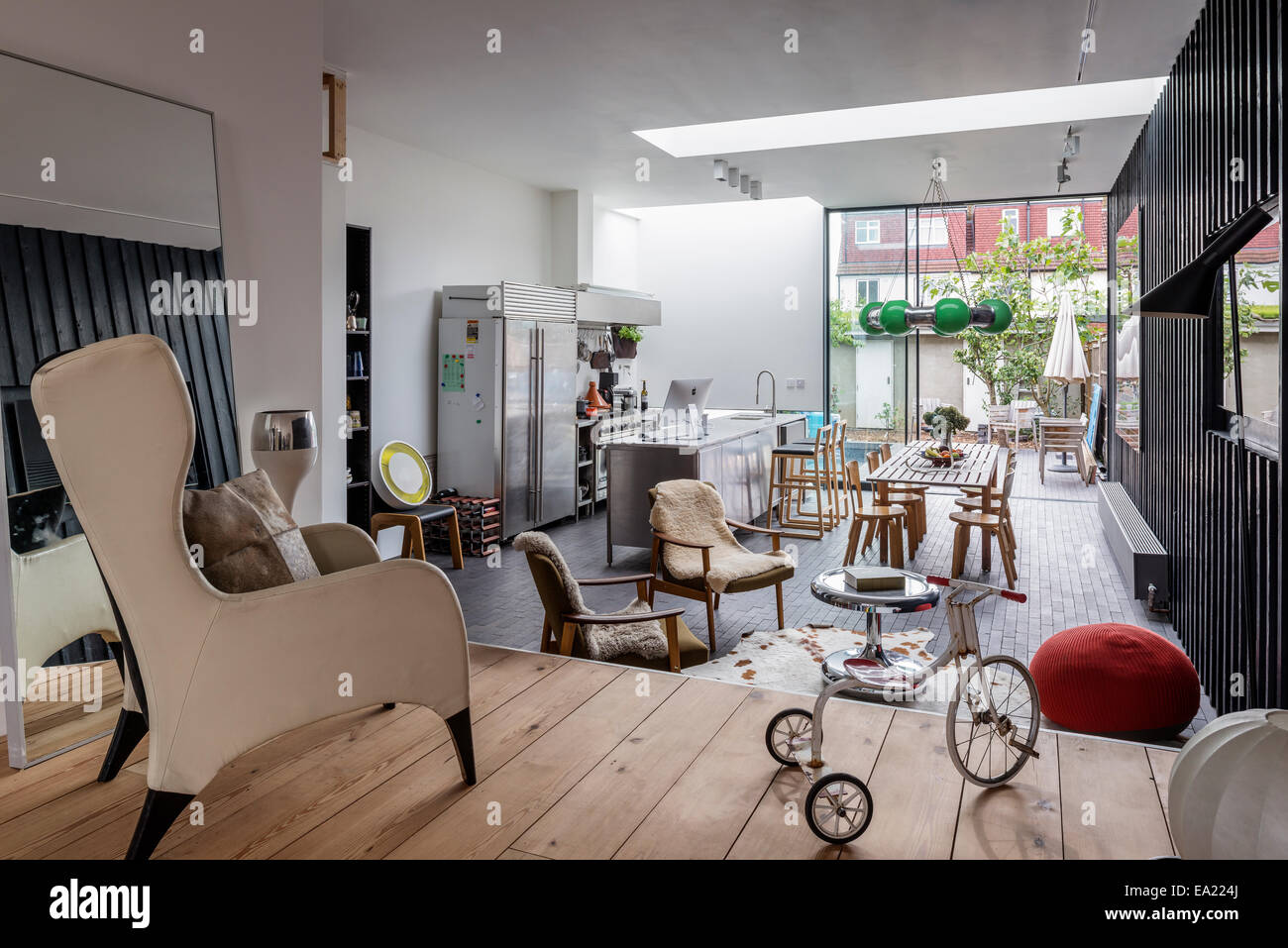 Cuisine moderne salon avec fauteuil de type bergère et tricycle en premier plan. Banque D'Images