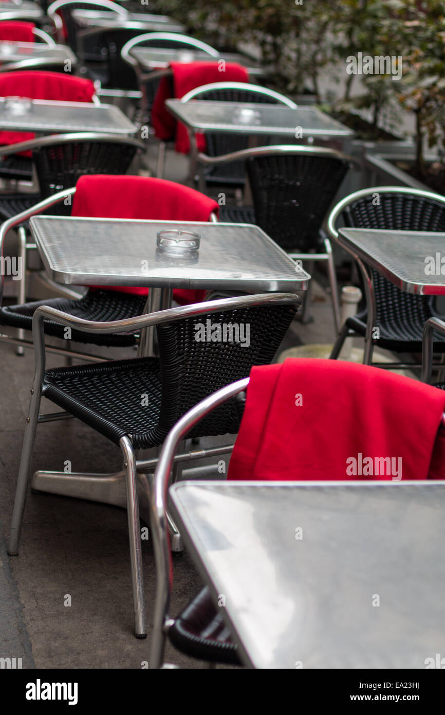 Café-terrasse avec chaises en osier, en plastique et des couvertures rouges Banque D'Images