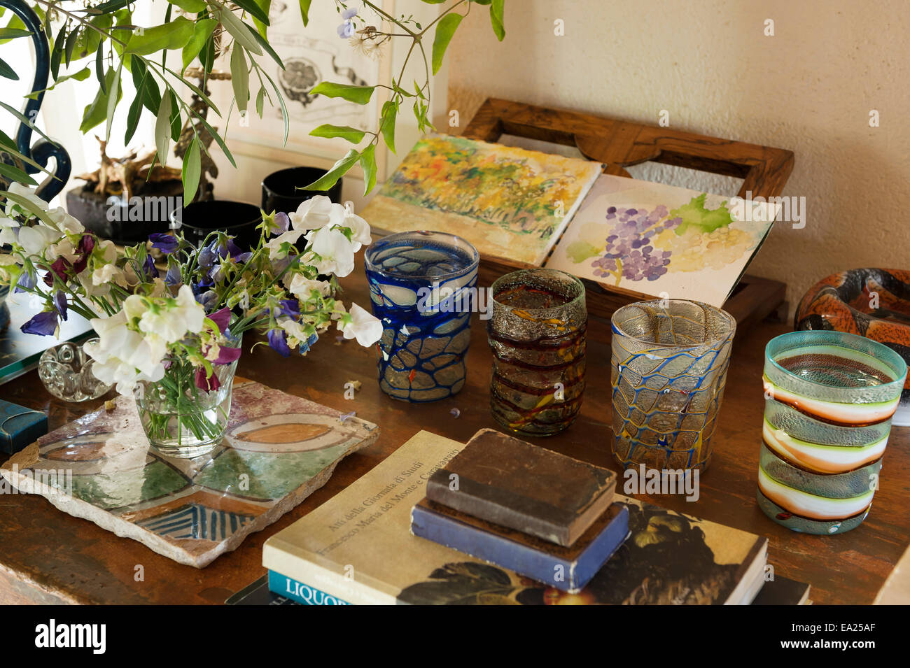 Rangée de tasses en verre sur table en petites aquarelles et vase de fleurs de pois. Banque D'Images