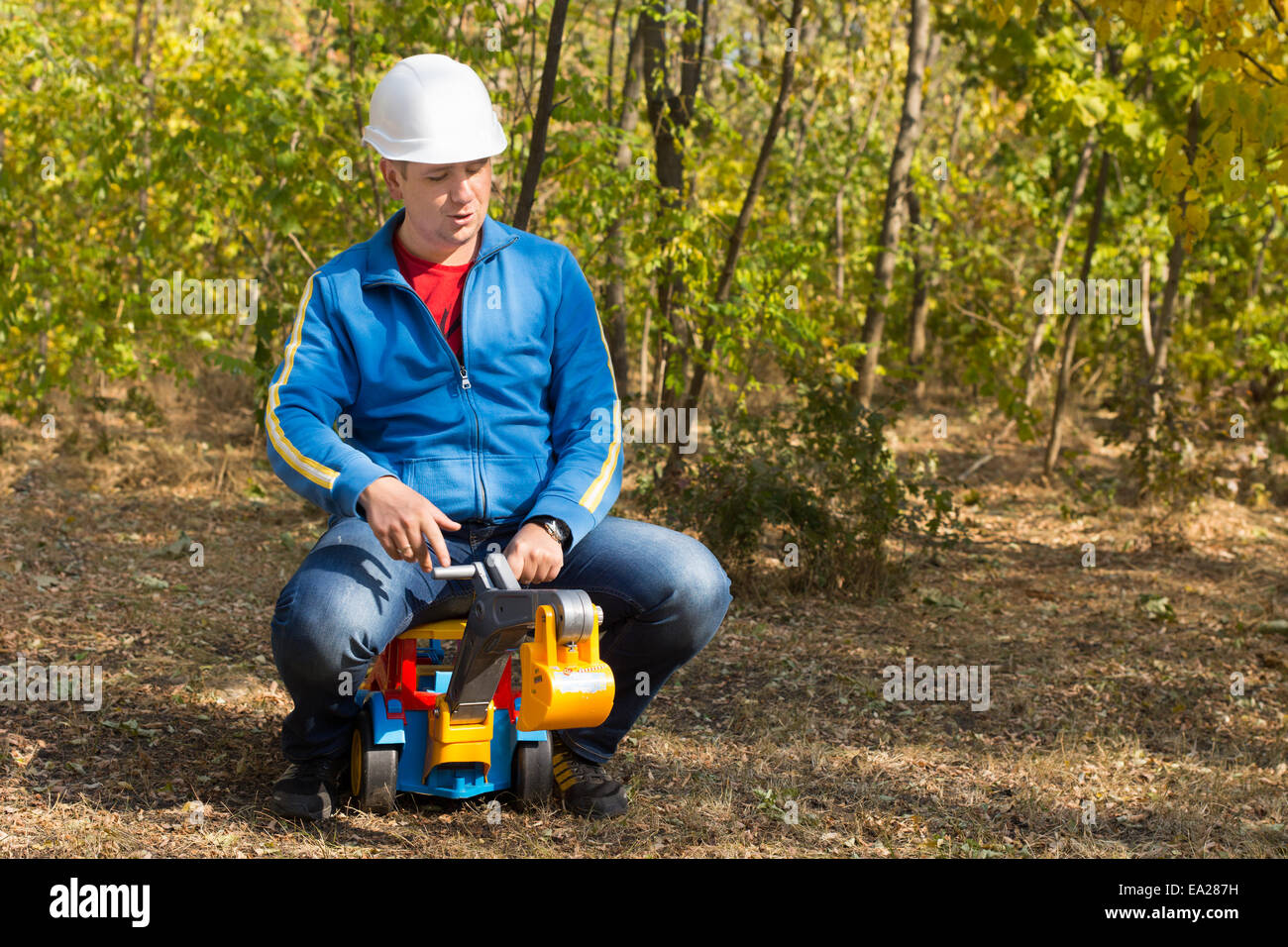 Close up Moyen-Âge l'homme à veste bleue avec le casque blanc équitation un camion Toy de l'autre. Banque D'Images